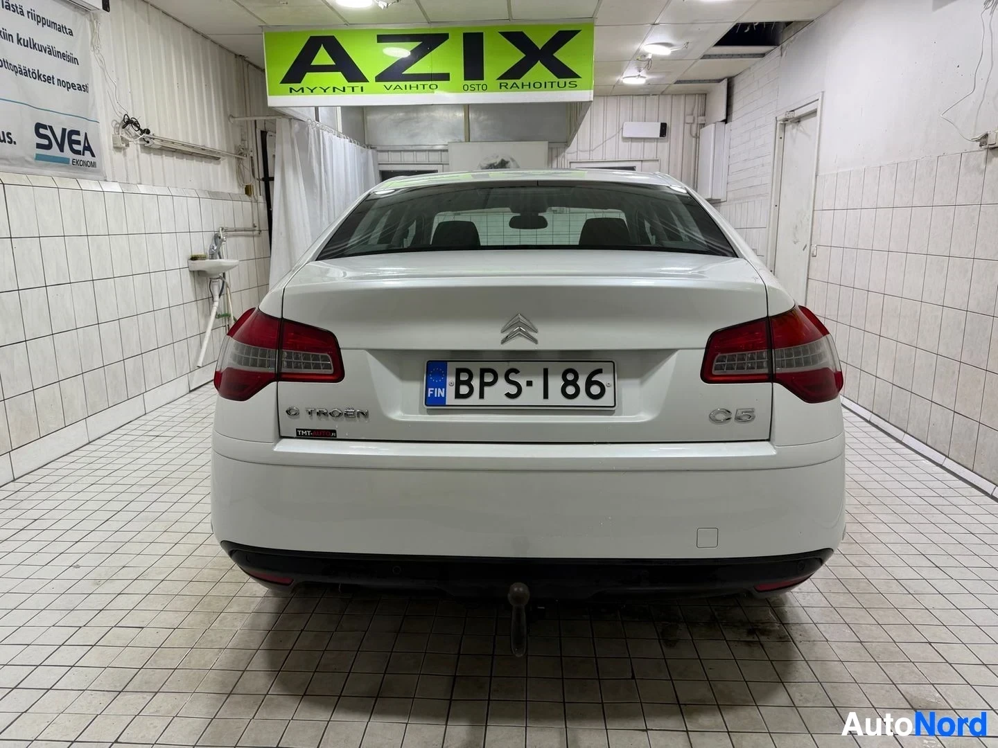 Takaa: Valkoinen Citroen C5 sedan näkyy takaa, sisätiloissa. Rekisterikilpi näkyy