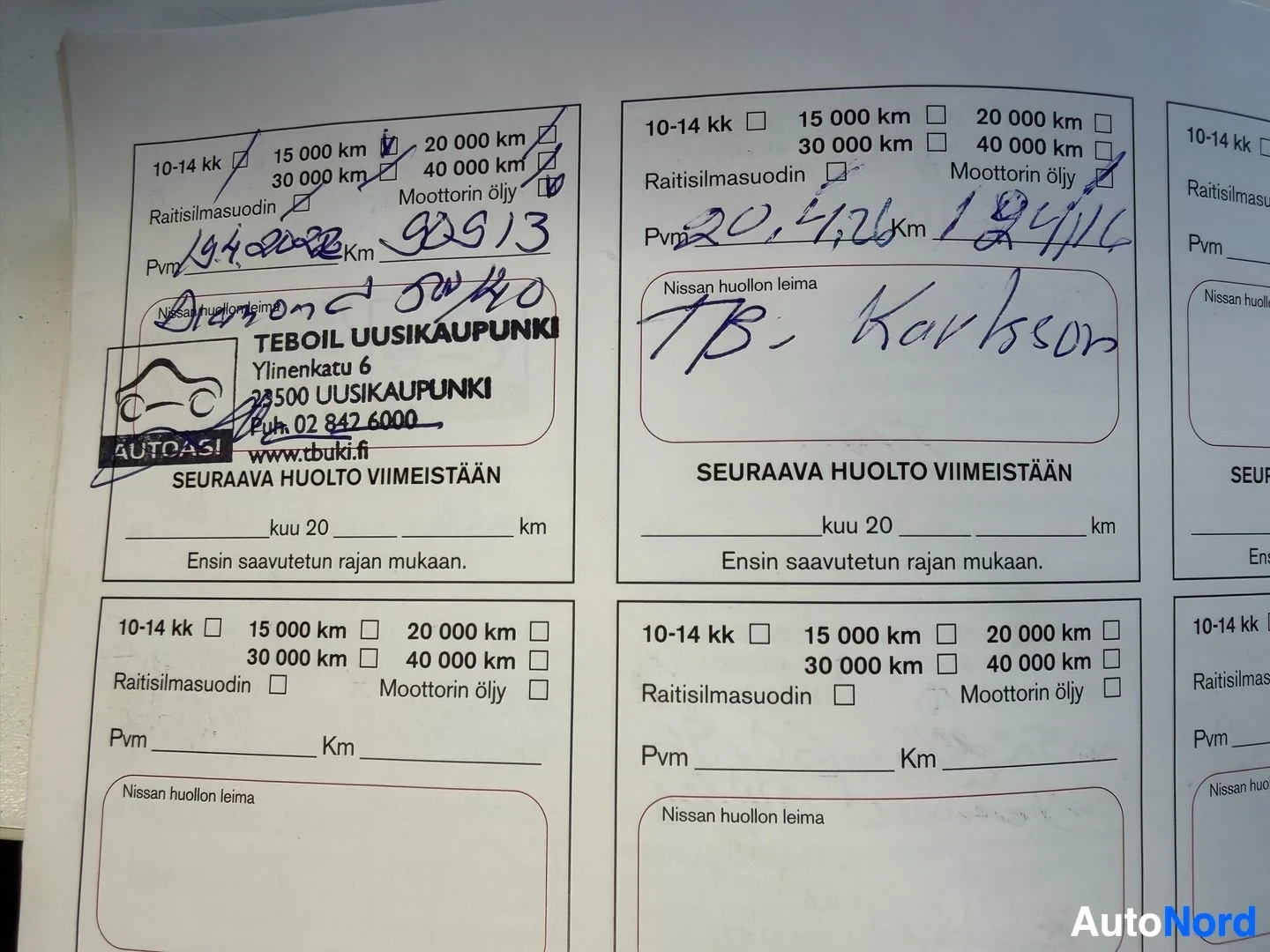 Asiakirja: Nissan huolto-ohjelma palvelukirjan sivuja, jossa käsin kirjoitettuja merkintöjä kilometreistä ja päivämääristä sekä TEBOIL Uusikaaupungin merkkiliikkeen leima.
