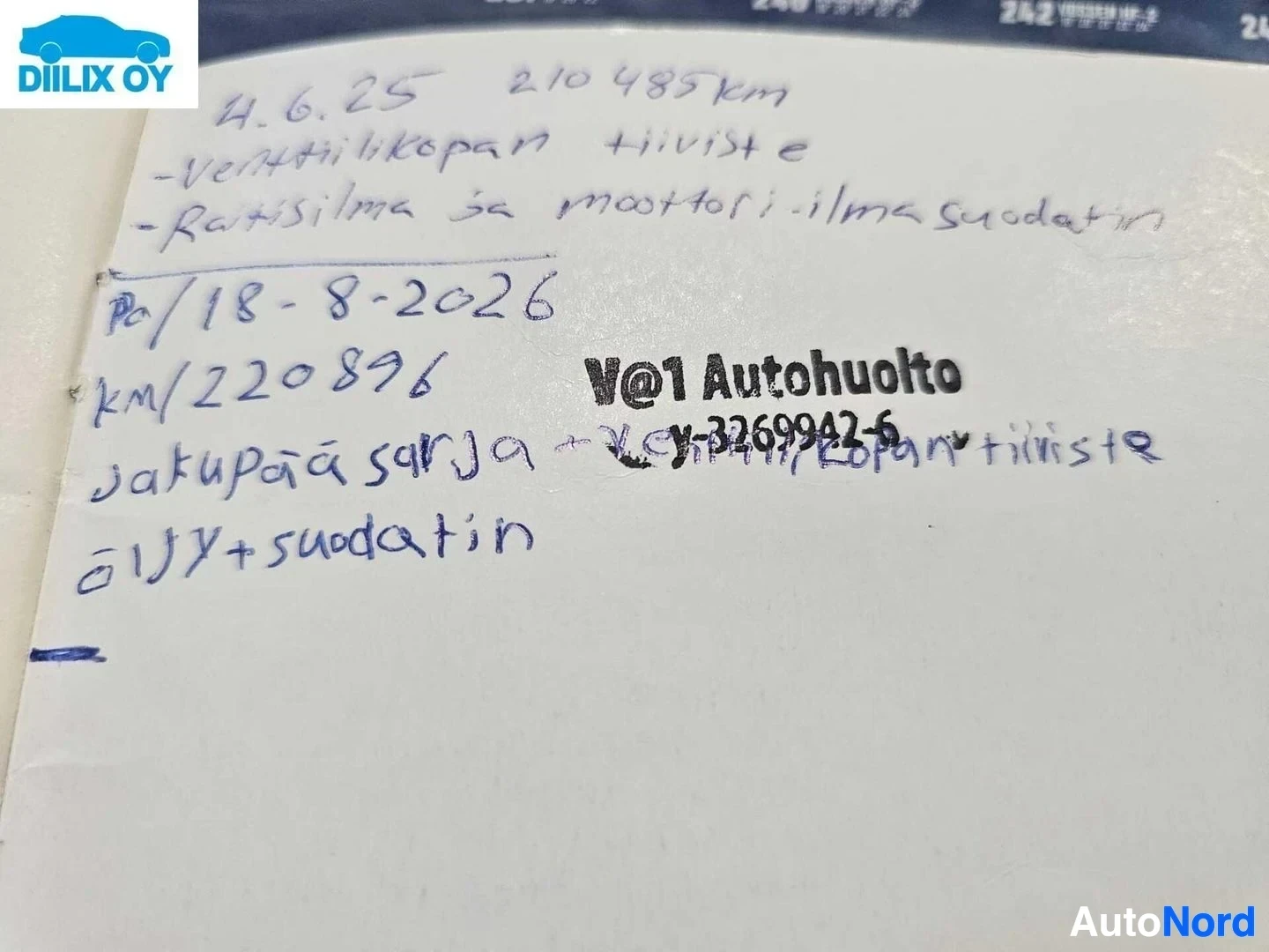 Asiakirja: Käsinkirjoitettu muistilappu sinisellä kynällä, jonka teksti sisältää päivämäärän, ajokilometrit ja automyyntiliikkeen nimen