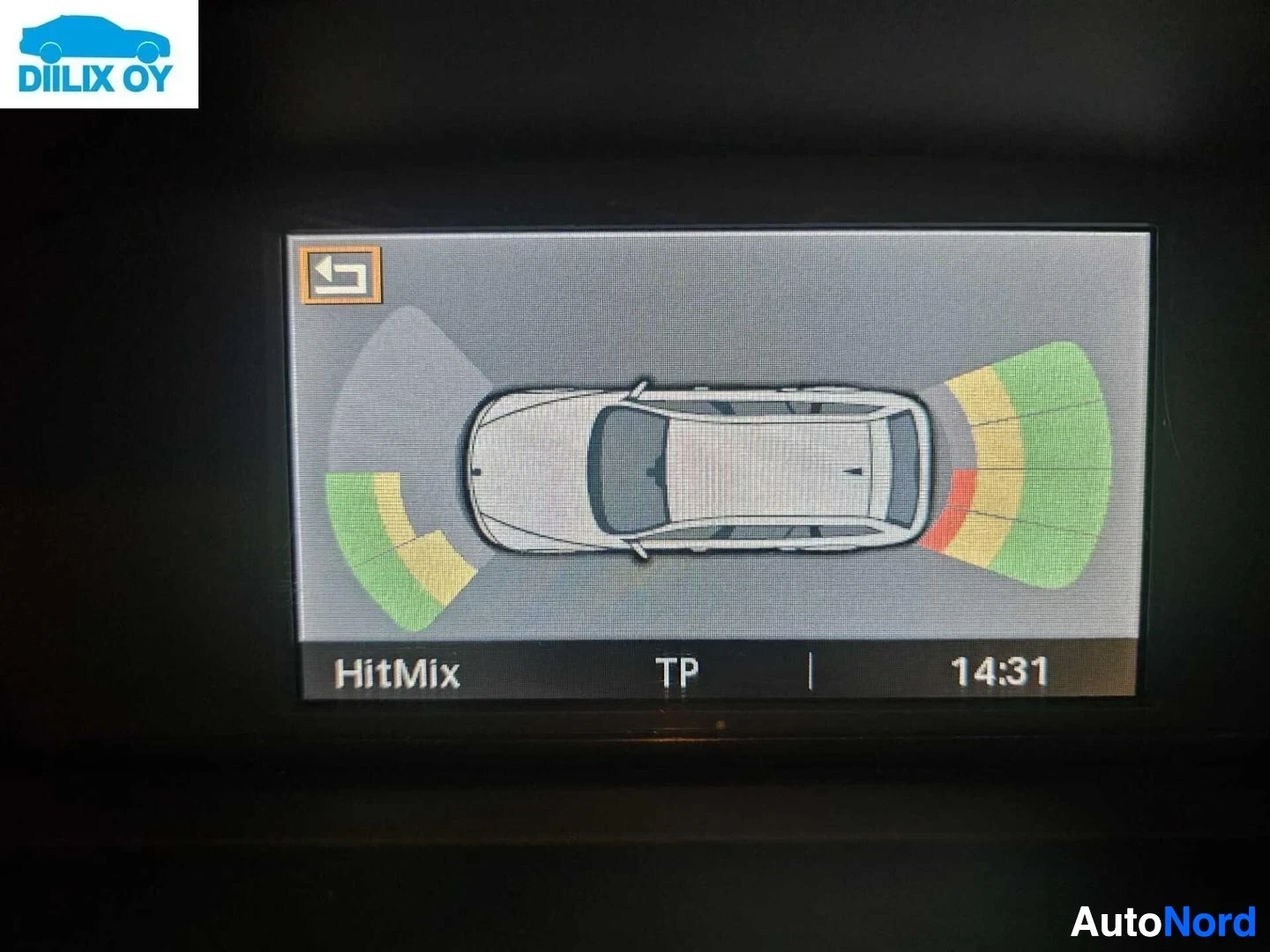 Yksityiskohta: BMW-infotainment-näytö, jossa näkyy 'HitMix'-tekstillä varustettu pysäköintiantennisysteemi-kaavio väri-indikaattorein