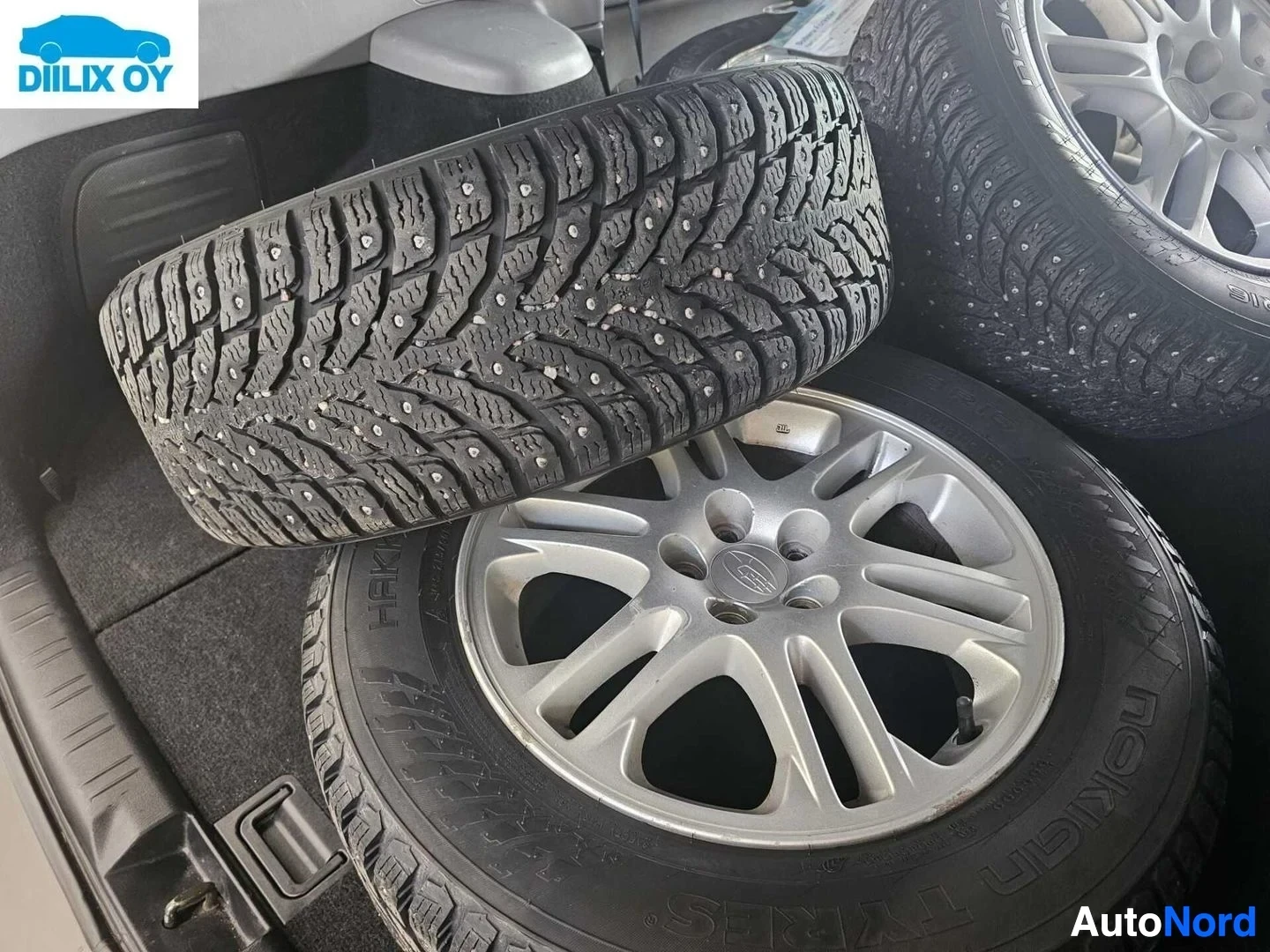 Yksityiskohta: Säilytetyt talvirenkaat ja alumiinivantteet, näkyy talvirengassa nastat ja vanteissa Subaru-merkintä.