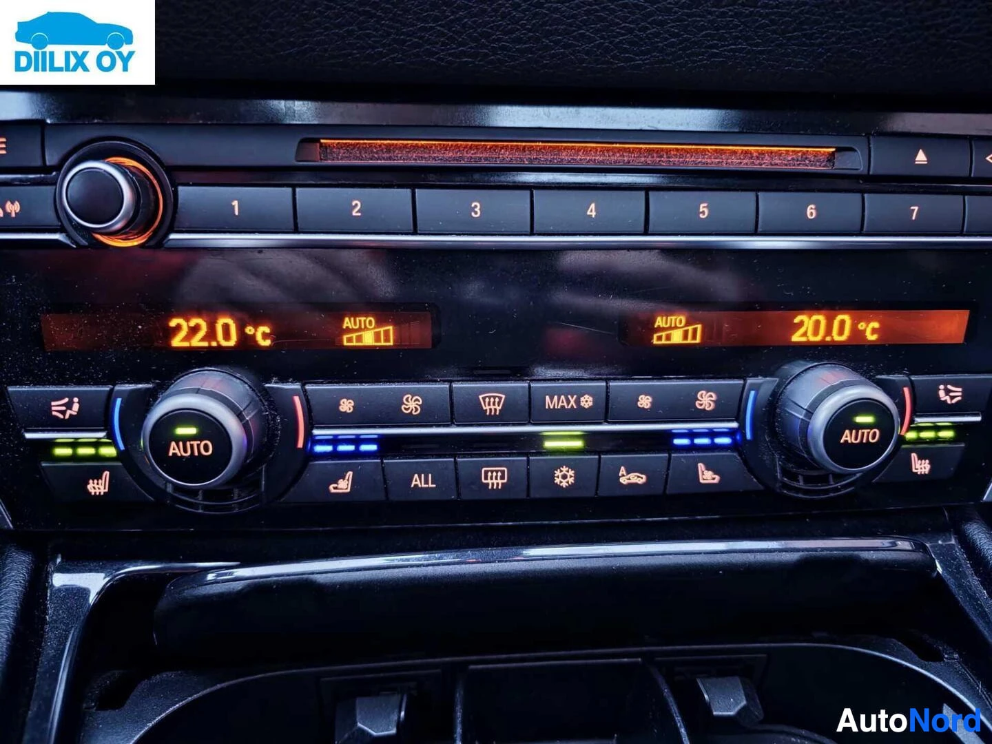 Yksityiskohta: Ilmastoinnin ohjauspaneeli näyttää kaksi aluetta: vasemmalla näkyy 22,0 °C AUTO-asetuksella ja oikealla 20,0 °C AUTO-asetuksella. Paneelissa näkyy myös FM-radio