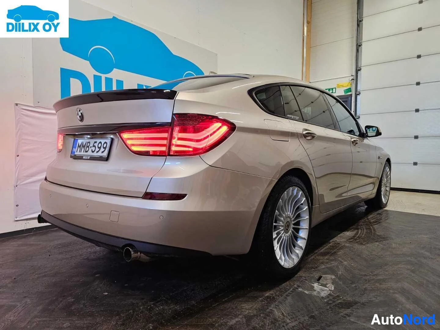Takaviisto: Hopeanvärinen BMW Gran Turismo näkyy takanäkymästä oikealle kääntyneenä. Takavalaisimet palavat punaisella, takatalli, rekisterikyltti ja harmaanvalkoin