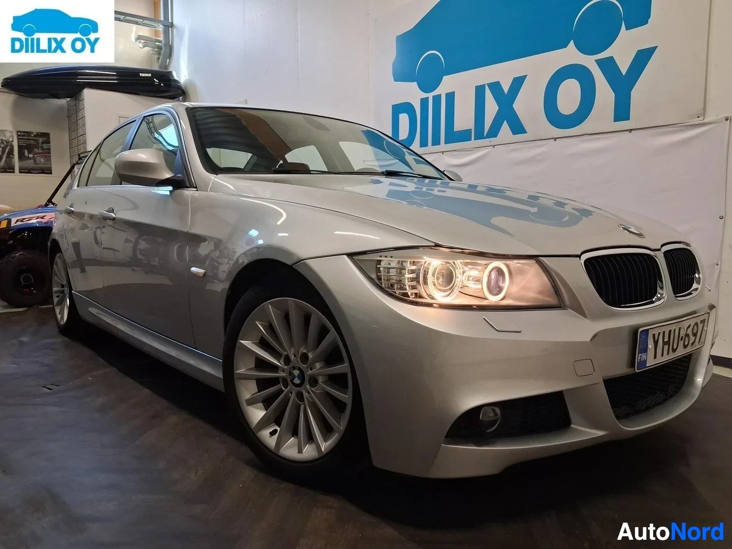Etuviisto, nokka vasemmalle: Hopeanvärinen BMW 318-sedan kuvausalustalla esittää etupuolen vasemmalta. Auton rekisterikilvessä. LED-päivänvalot näkyvät