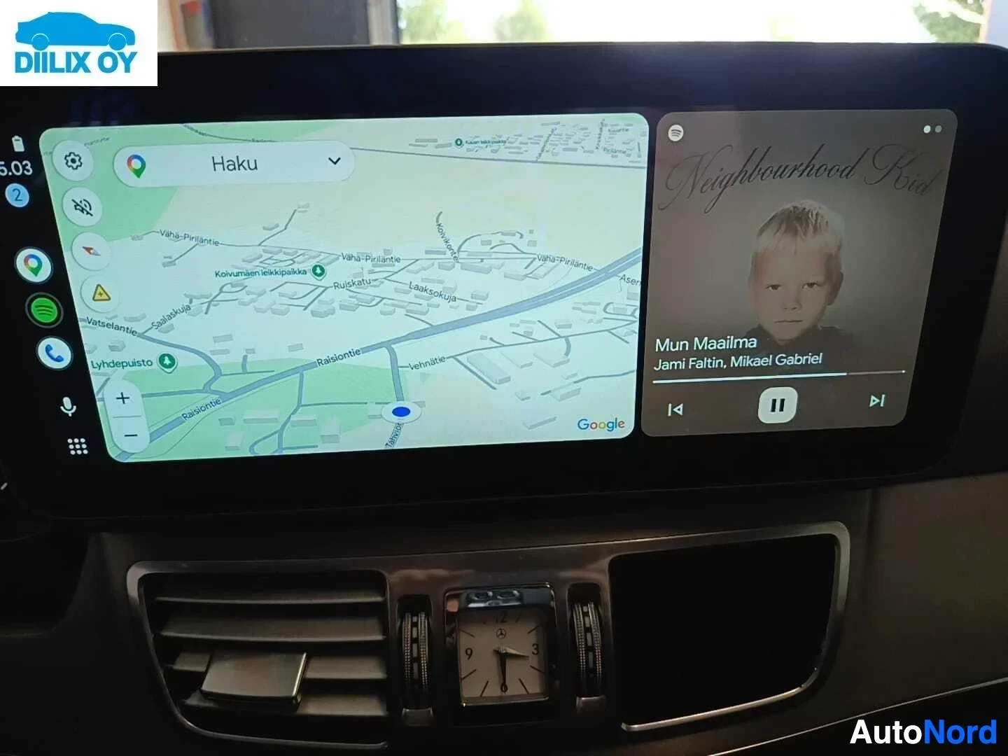 Yksityiskohta: Infotainment-näyttö, Google Maps näkyvissä vasemmalla, musiikki-soittoliittymä oikealla, ilmanvaihtoaukot näkyvissä alhaalla