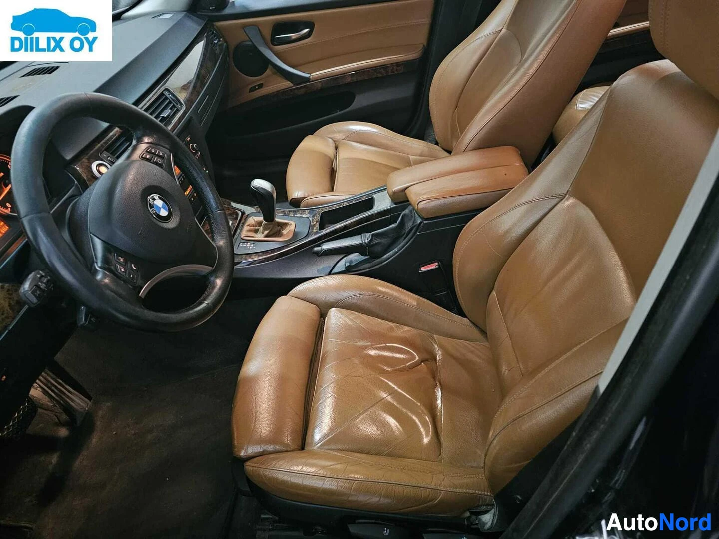 Etuistuimet: Auton sisätila, ruskea nahkaverhoilu, mustanahkainen ohjauspyörä, BMW-logo näkyvissä, vaihteiston nuppi näkyvissä