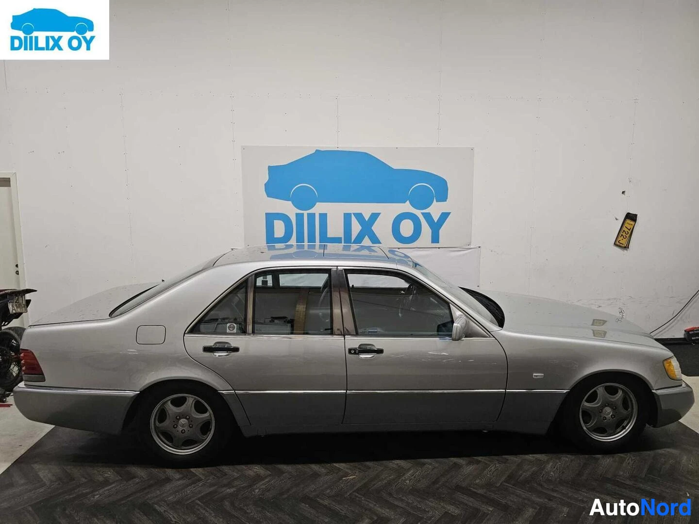 Sivulta: Hopeanvärinen nelioven sedan oikea sivu näkyy täysiin sisätiloissa. Auto on kuvattu sivulta.