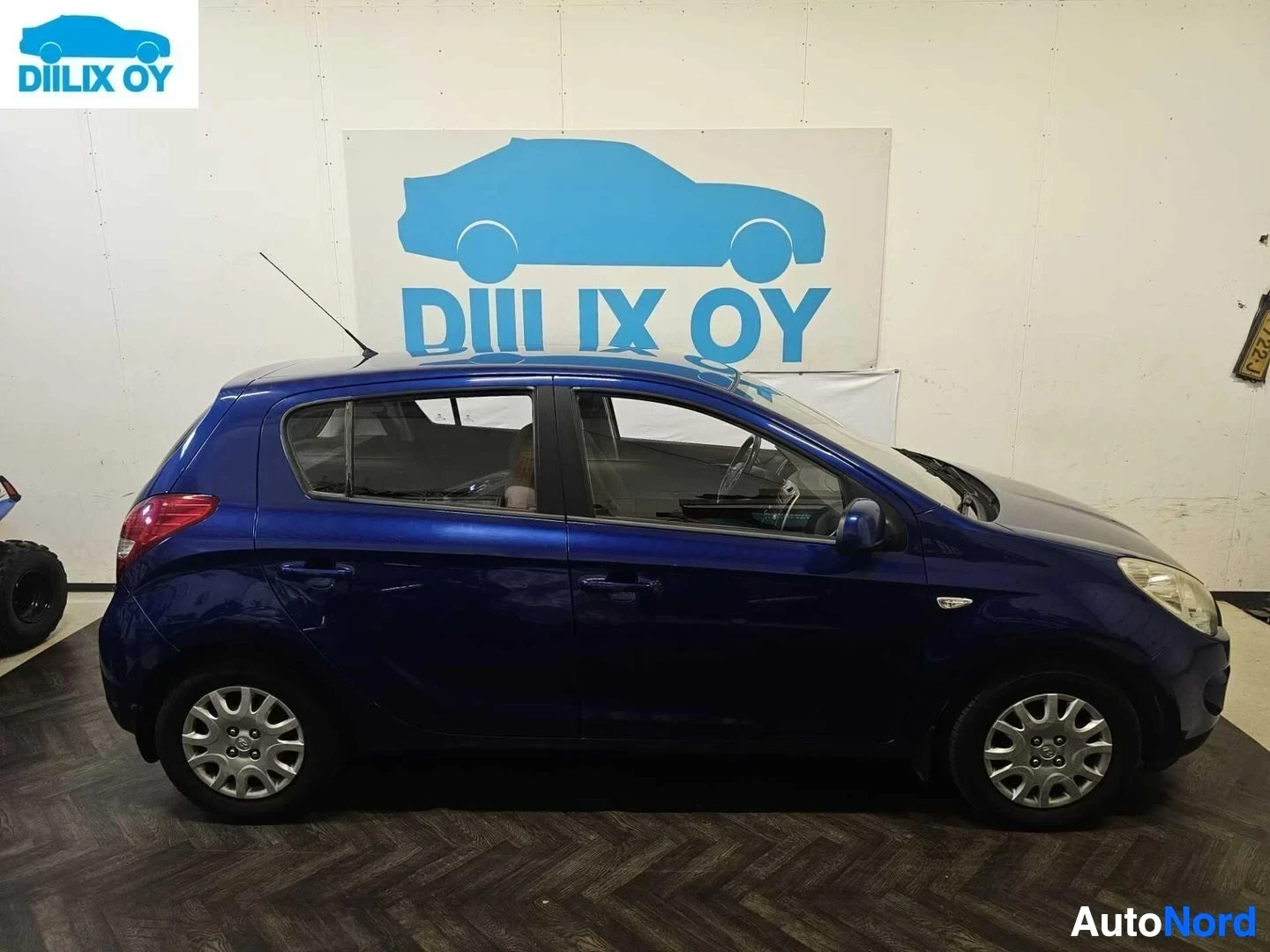 Sivulta: Sininen Hyundai i20 -henkilöauto sivu, sisätiloissa