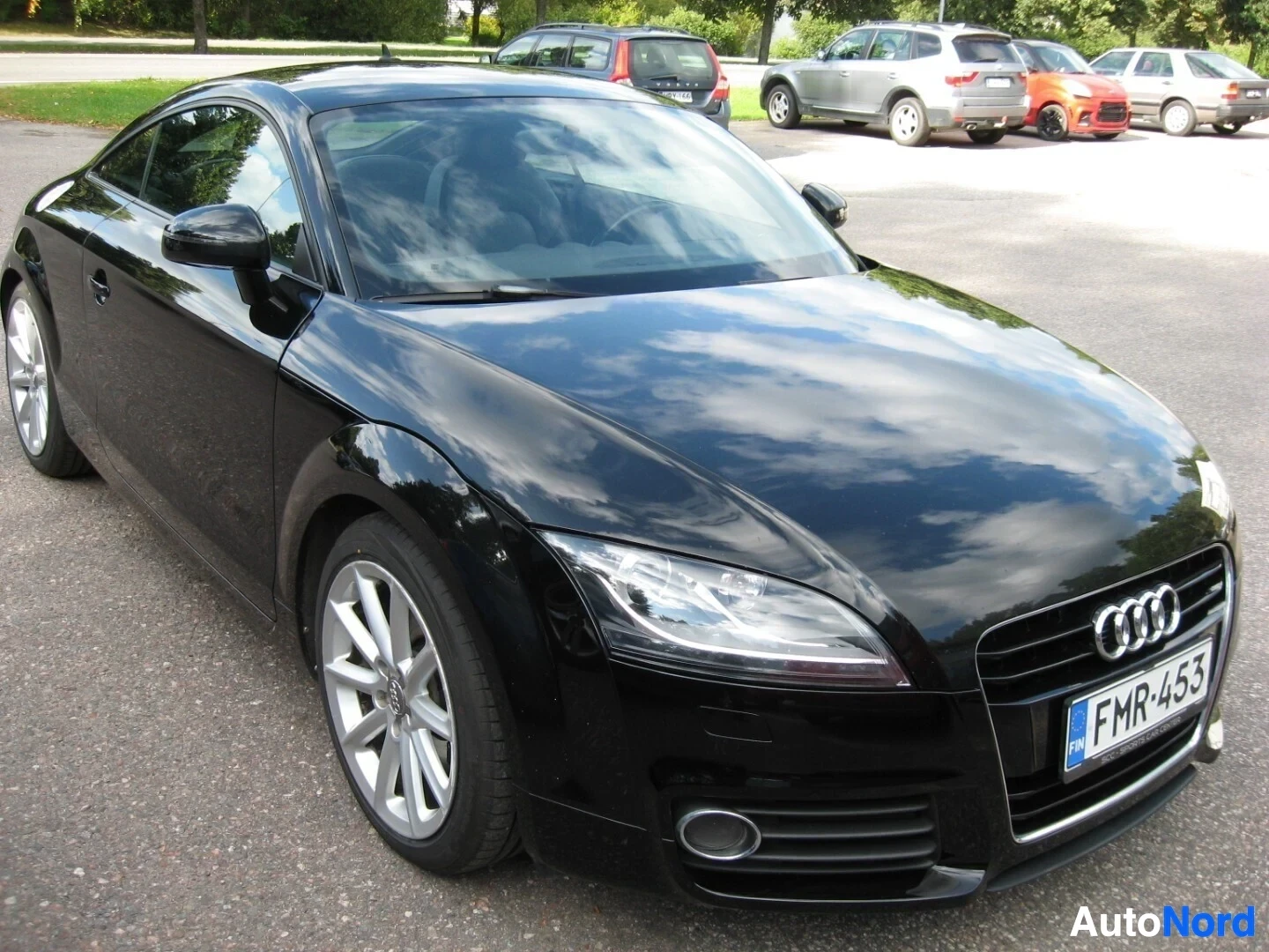 Etuviisto, nokka oikealle: Musta Audi TT -coupe kolmen neljänneksen näkymässä oikealta, rekisteritunnus näkyvissä edessä