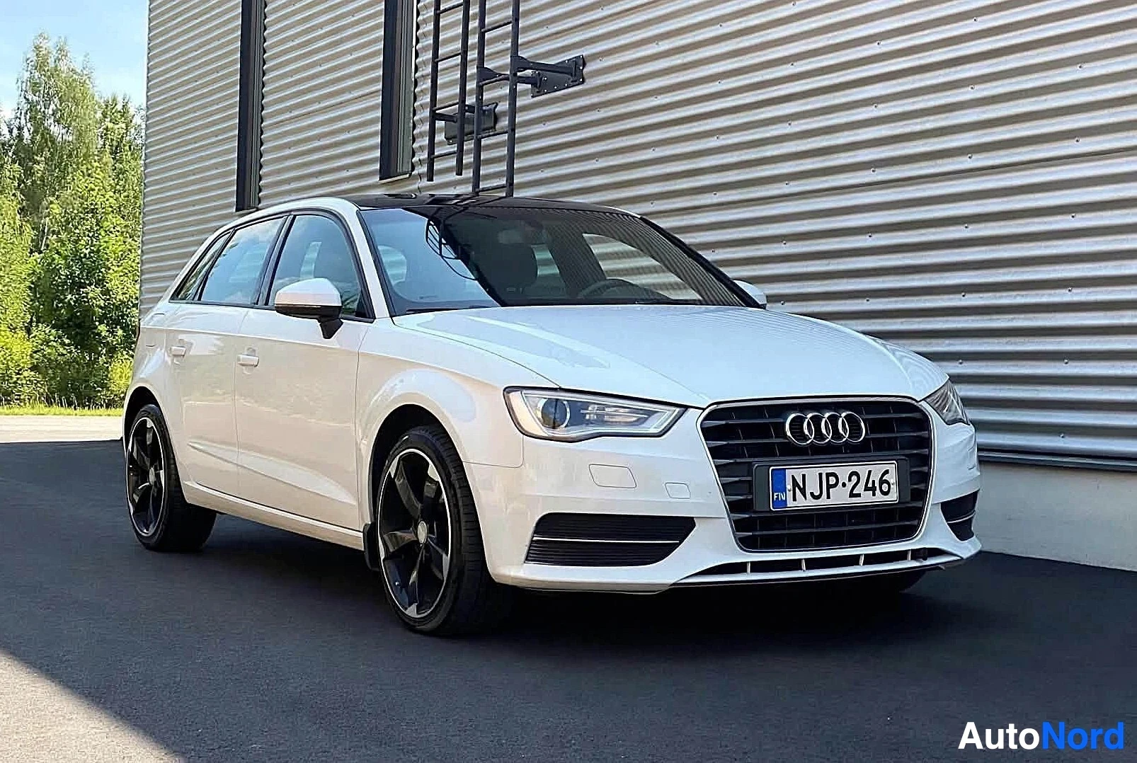 Etuviisto, nokka oikealle: Valkoinen Audi-auto vasemmalta puolelta kuvattuna, näkyvissä koko sivuprofiili ja etupuoli
