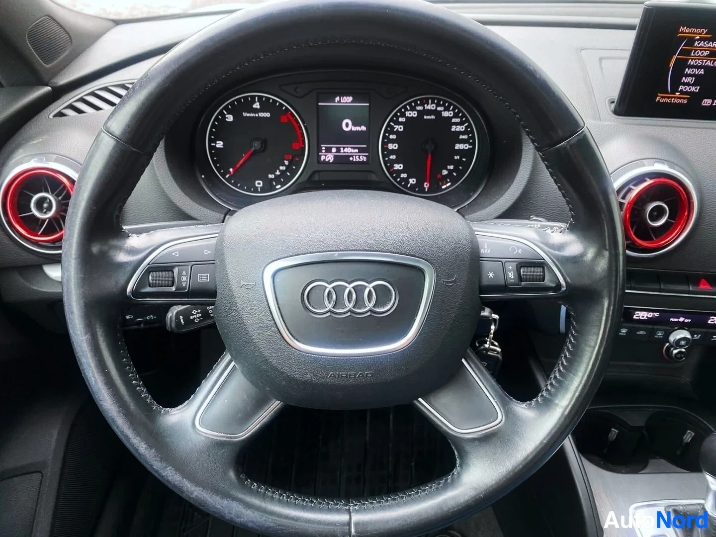 Yksityiskohta: Lähikuva ohjauspyörästä ja mittareyhdistelmästä: Audi-logo, kierroslukumittari ja nopeusmittari, jossa näkyy pieni display 0 km/h nopeudella ja muistoa sekä kaa