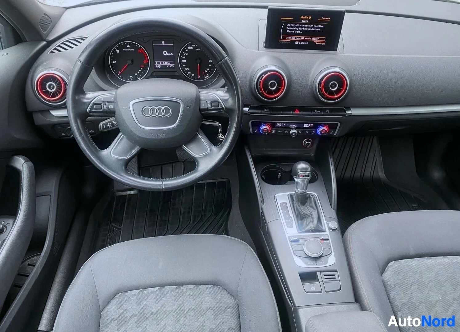 Ohjaamo: Kuljettajan näkökulma: Audi-logo ohjauspyörässä, kierroslukumittari, nopeusmittari, keskikonsoli punaisilla sisäänrakennetuilla ilmanvaihdon säätöpainikkeilla j