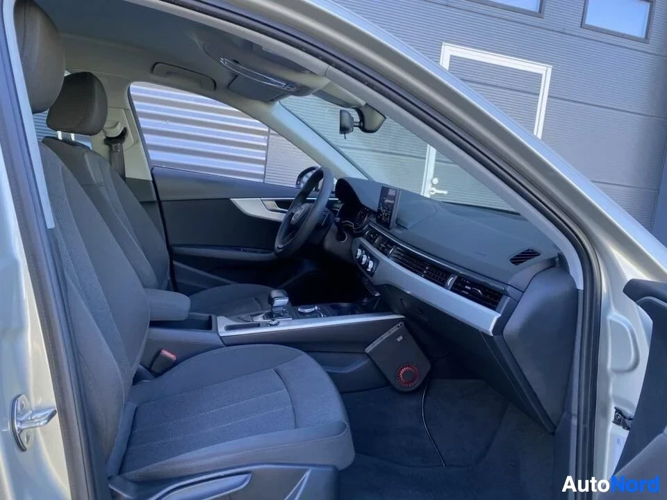 Etuistuimet: Auton etuistuimet ja ohjaamo sivusta; näkyy Audi-logo ohjauspyörässä, navigointijärjestelmä ja tummansininen tekstiilinverhoilu.