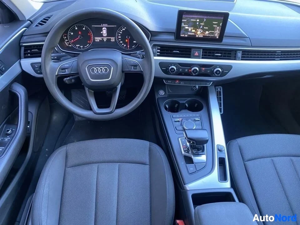 Etuistuimet: Auton ohjaamo edestä; Audi-logo ohjauspyörässä, digitaalinen mittaristo, navigointinäyttö ja kolmen pyörivän ilmastoinnin painikkeet.