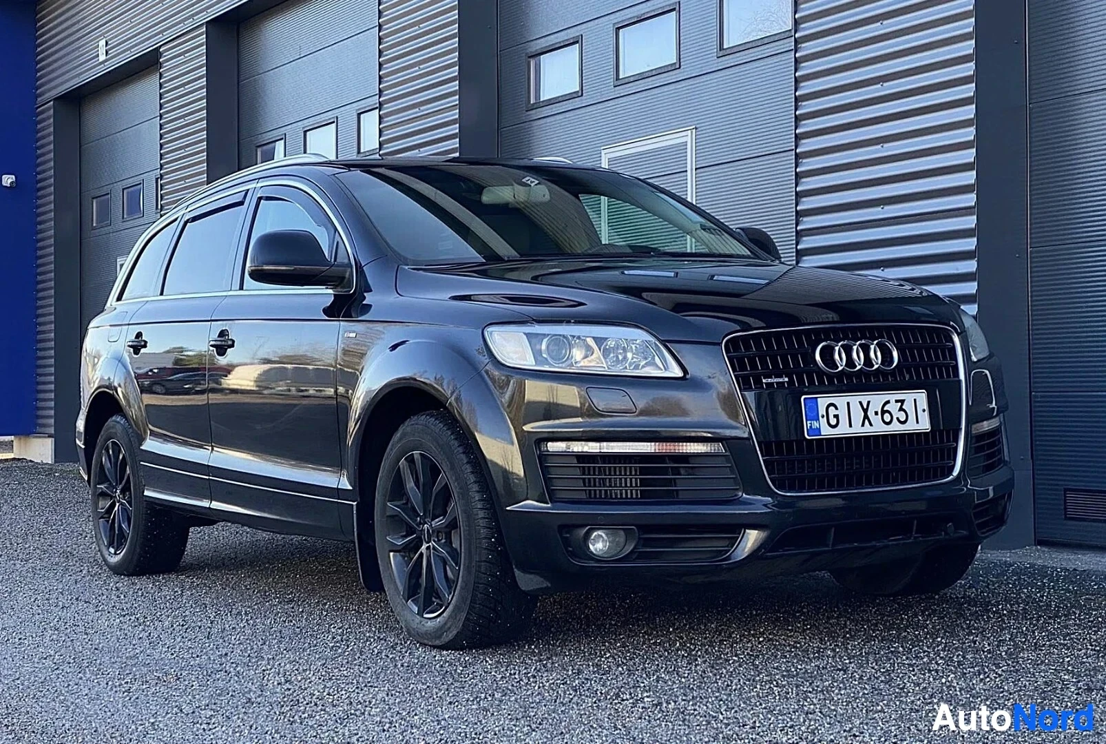 Etuviisto, nokka vasemmalle: Musta Audi Q7 -maastoauto edestä kuvattuna varikon seinustalla, rekisterikilpi näkyvillä