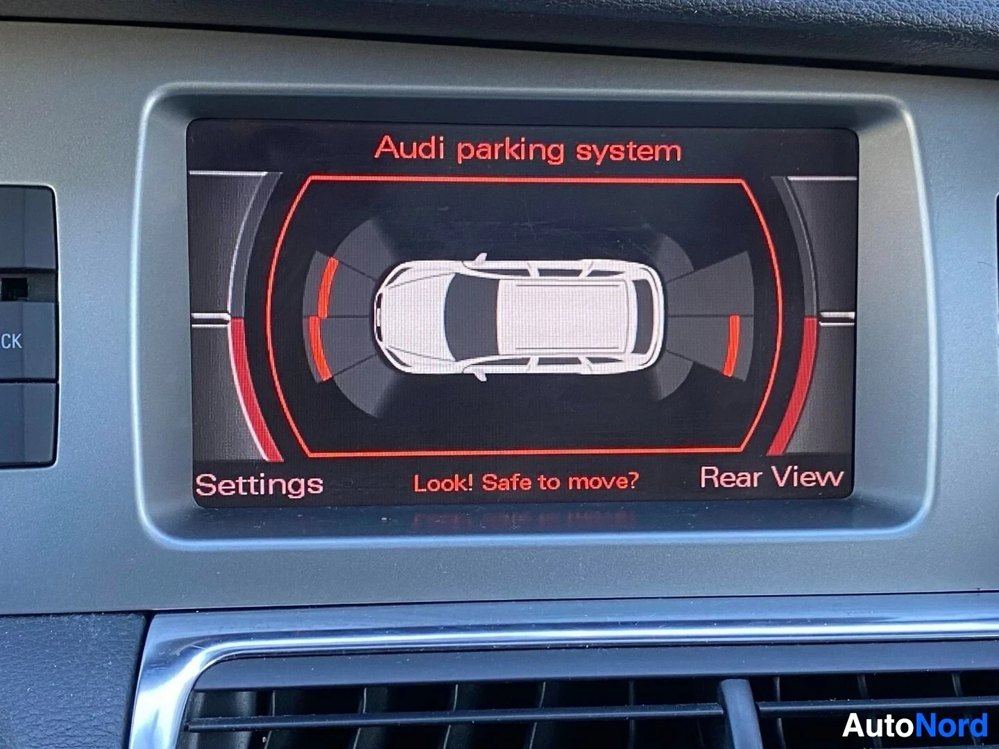Yksityiskohta: Audi paikoittumisjärjestelmän näyttö näyttää punaisen varoitusvihko ja kamerakuvaa autosta yläpuolelta.