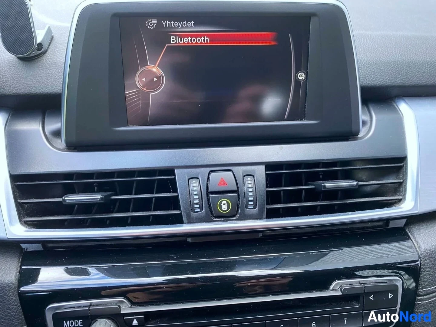 Yksityiskohta: Näyttöruudussa Bluetooth-yhteyden valikkokuvake, BMW Yhteydessä -kuvake ja punainen Bluetooth-otsikko.