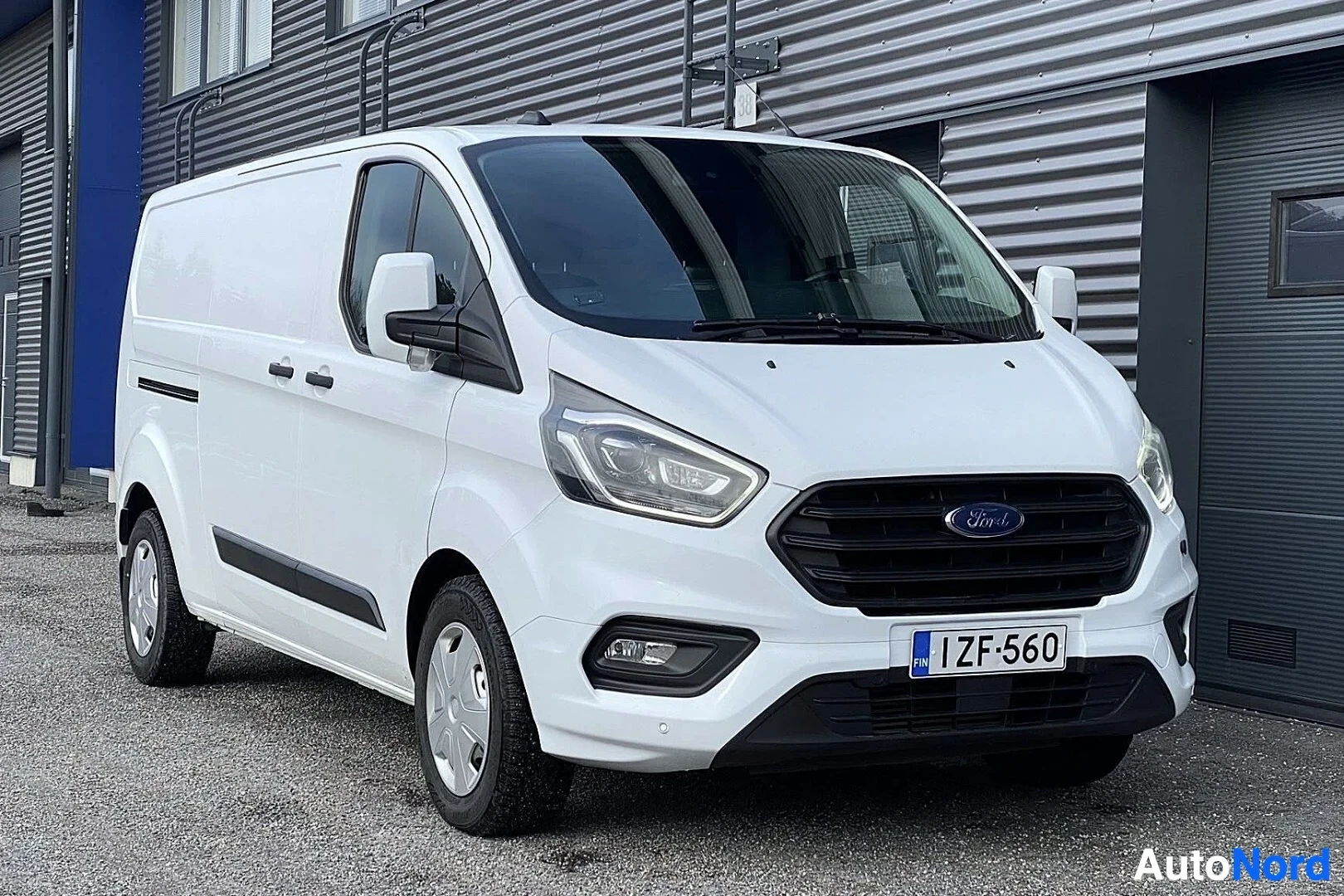Edestä: Valkoinen Ford Transit Custom -pakettiauto kuvattu edestä, rekisterikilvessä