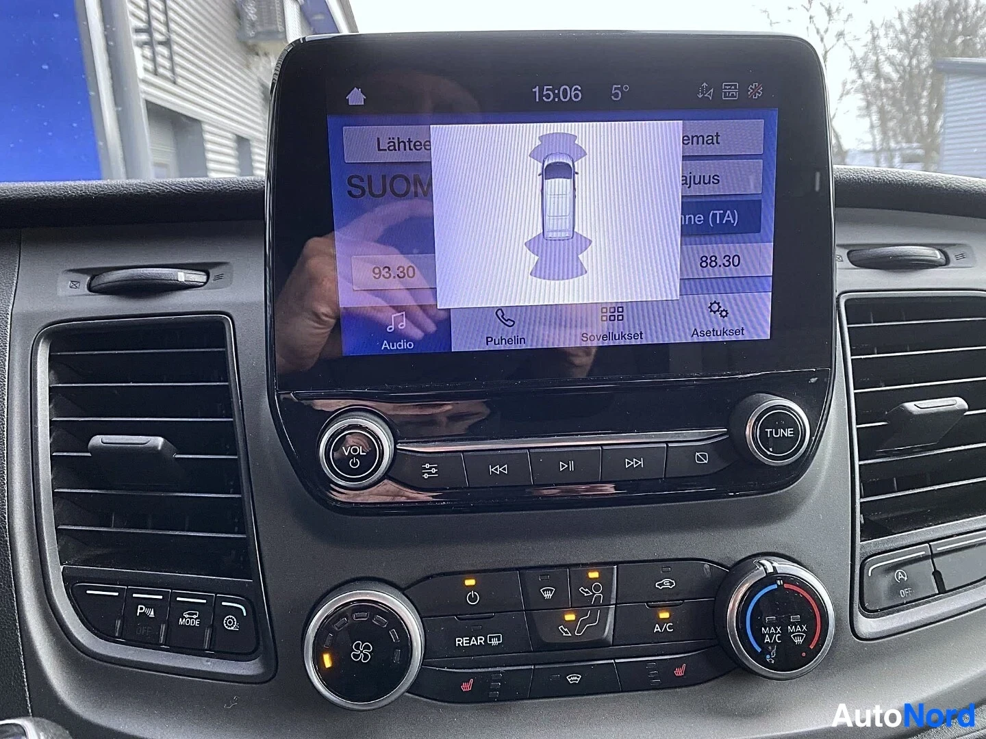 Yksityiskohta: Kosketusnäytön 360-kamera näkymä sekä radio-ohjaimet, kellonaikainen 15:06 ja lämpötila 5°C näkyvissä.