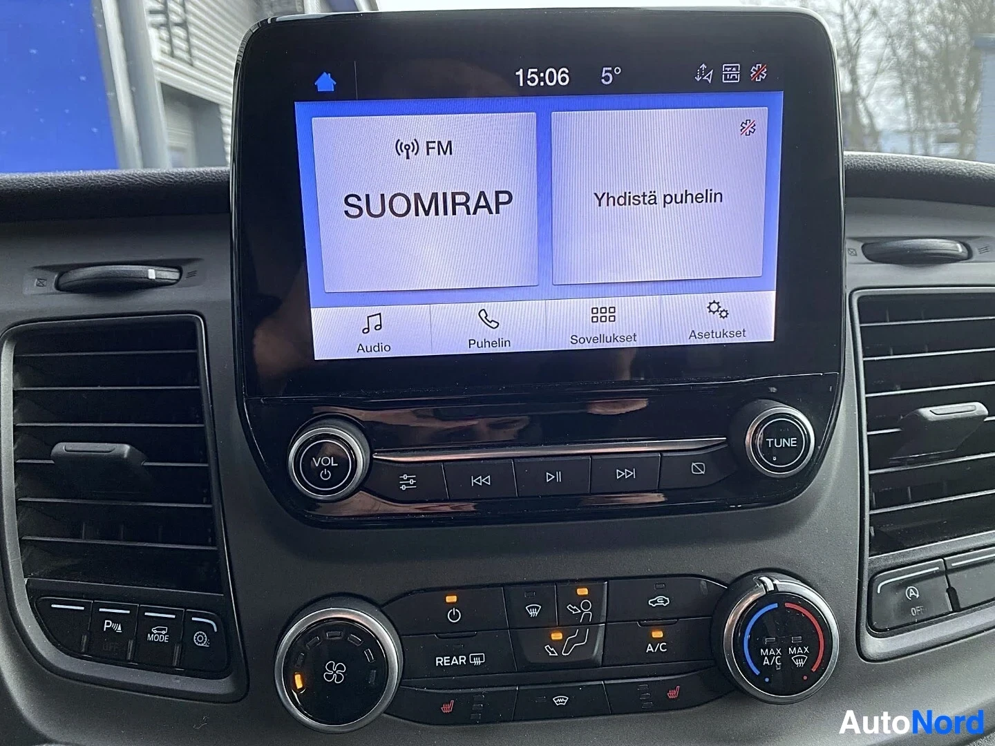 Yksityiskohta: Kosketusnäyttö näyttää FM-radiota, SUOMIRAP-kanava tuned, Yhdistä puhelin -vaihtoehto näkyvissä.