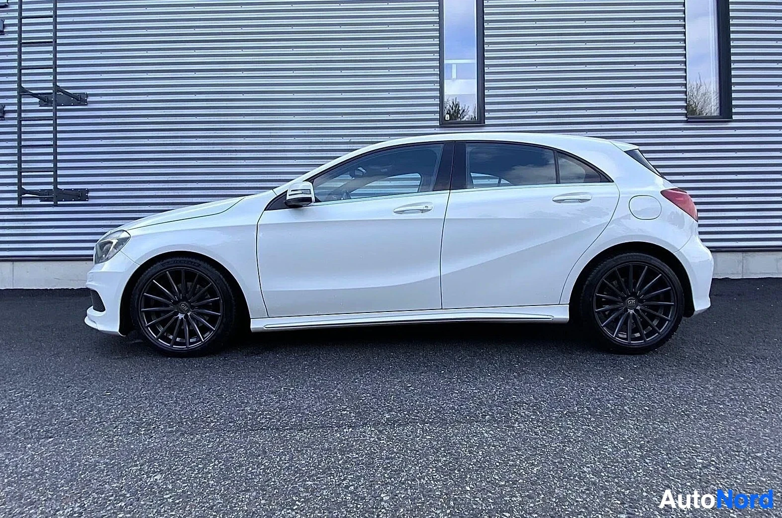 Sivulta: Valkoinen Mercedes-Benz A-sarja viistoperä, näkymä sivusta oikealta, parkissa.