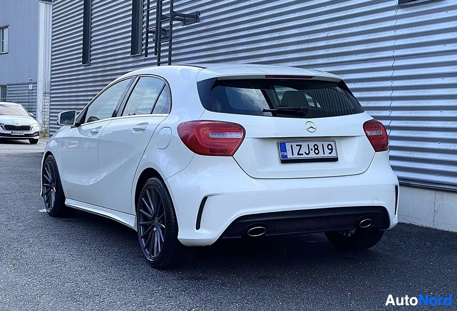 Takaviisto: Valkoinen Mercedes-Benz pienoisauto takakolmiasentodesissa. Näkyvät punainen takavalo, mustat vanteet, ja kaksoisputkesta pakoputkea. Rekisterikyltti