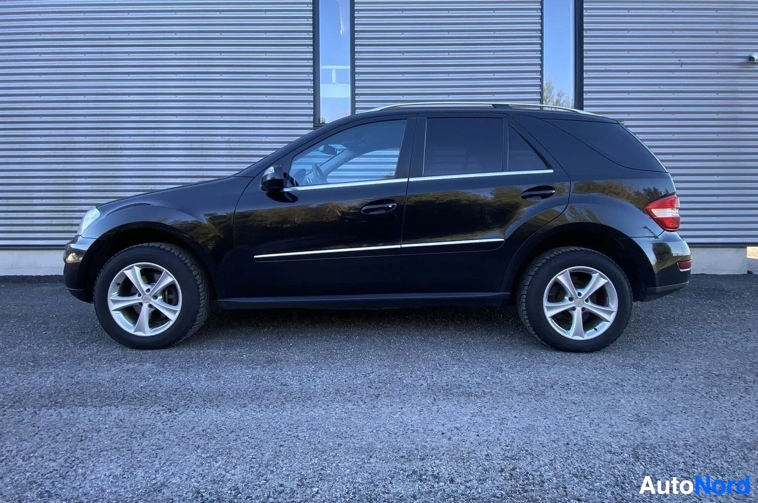 Sivulta: Sama musta Mercedes-Benz ML 350 CDI maastoauto sivusta, näkyvissä kuuden loimen vanteet ja punaiset takavalot.