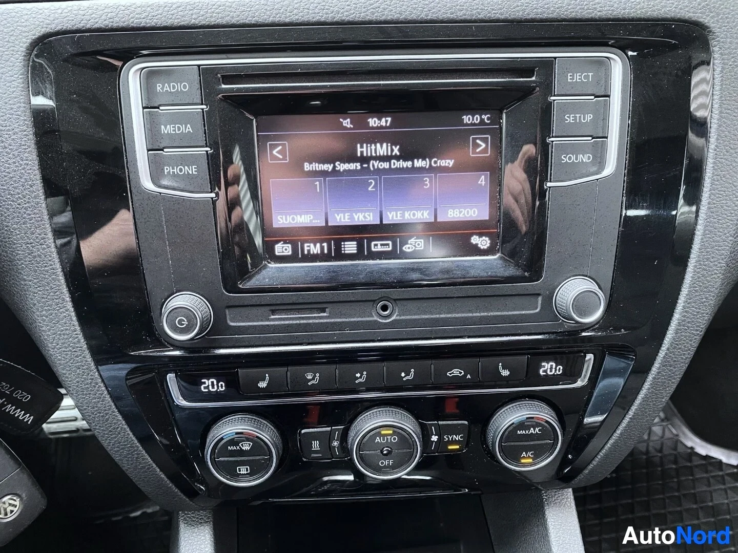 Yksityiskohta: Auton infotainment-näyttö näyttää HitMix-radiostatiota ja musiikkikappale Britney Spearsilta, näkyvillä neljä radiokanavanvalintapainiketta.