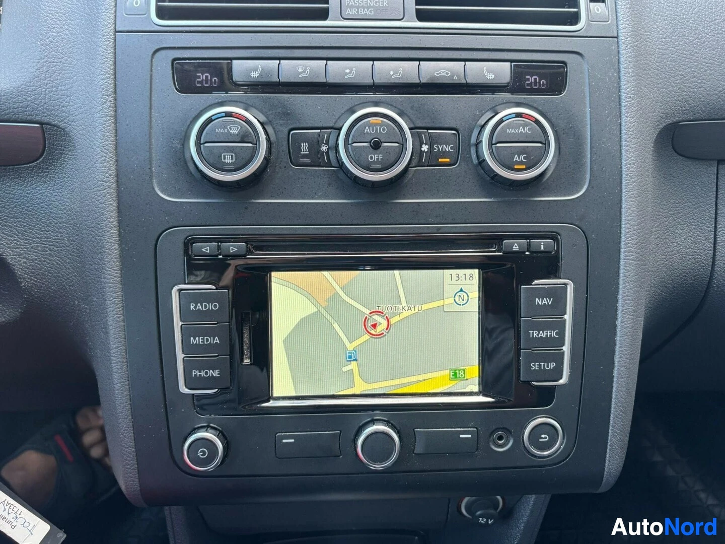 Yksityiskohta: Auton ilmastoinnin ja infotainment-järjestelmän ohjainpaneeli. Kolme ilmastointipainiketta, SYNC-painike, navigointi kartalla näkyvillä näytöllä. Lämpötilan näy