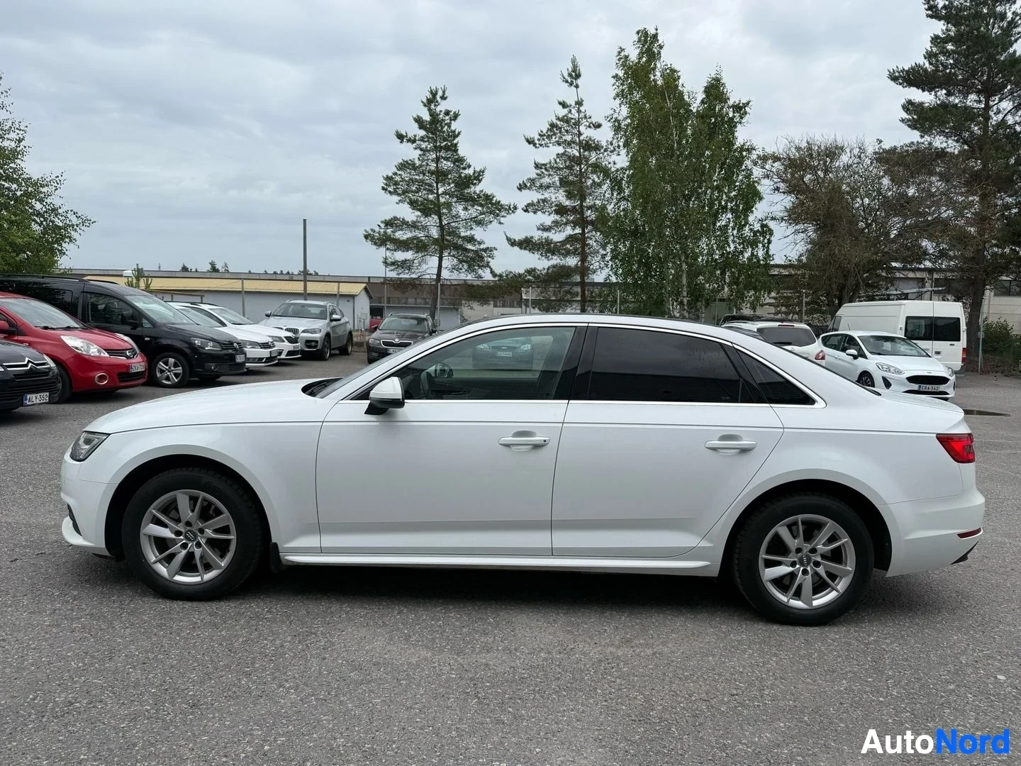 Sivulta: Valkoinen Audi A4 sedan sivusta vasemmalle kuvattuna. Neliosainen ovi ja hopeanväriset vanteet näkyvät.