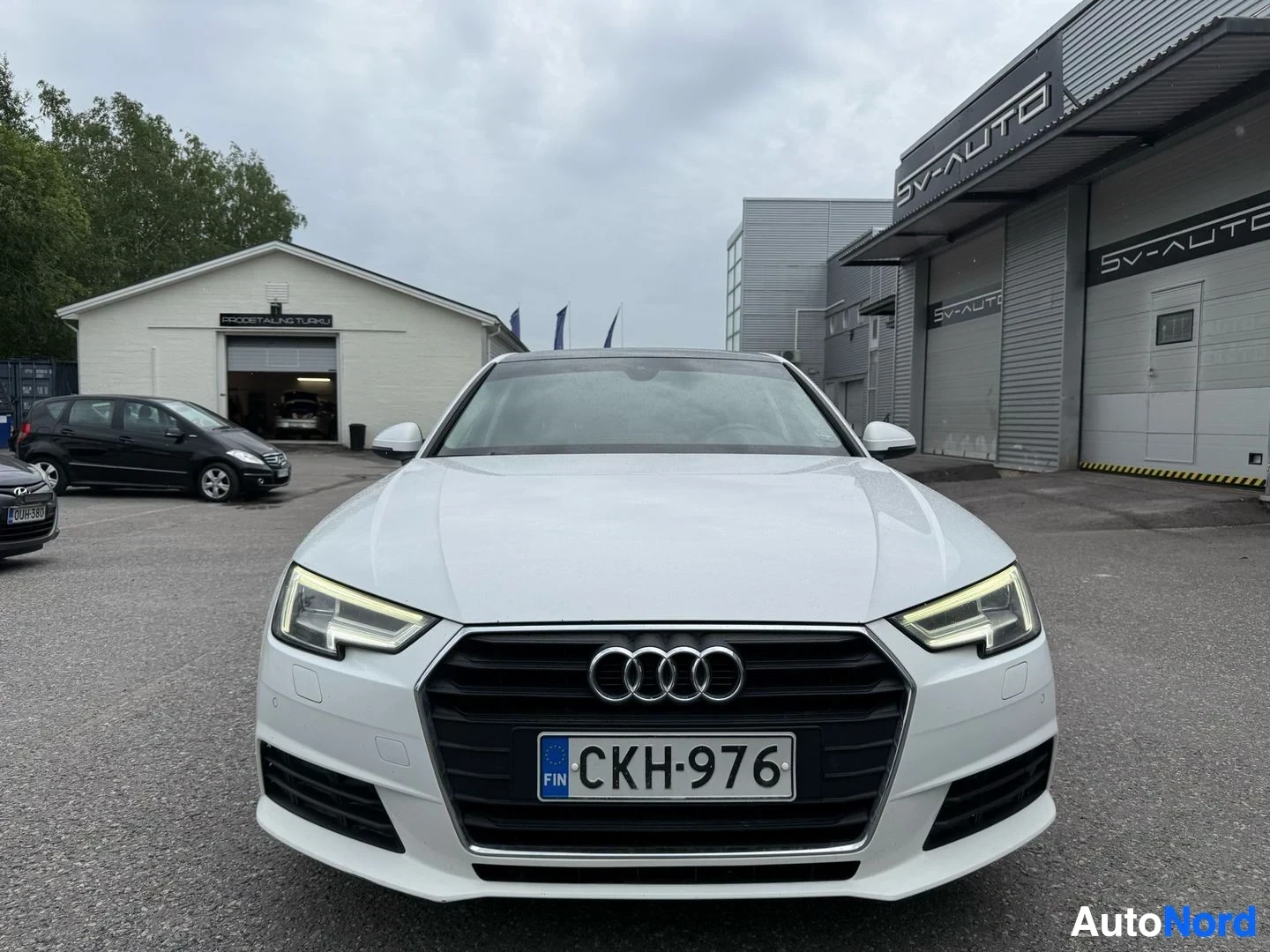 Edestä: Valkoinen Audi A4 sedan edestä kuvattuna suoraan. LED-päivänvalot näkyvät. Rekisterikilpi näkyy eteen