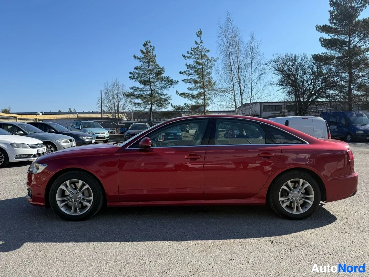 Sivulta: Punainen Audi A6 Avant station wagon näkyy sivusta, alloy wheels, pitkä runko näkyvissä