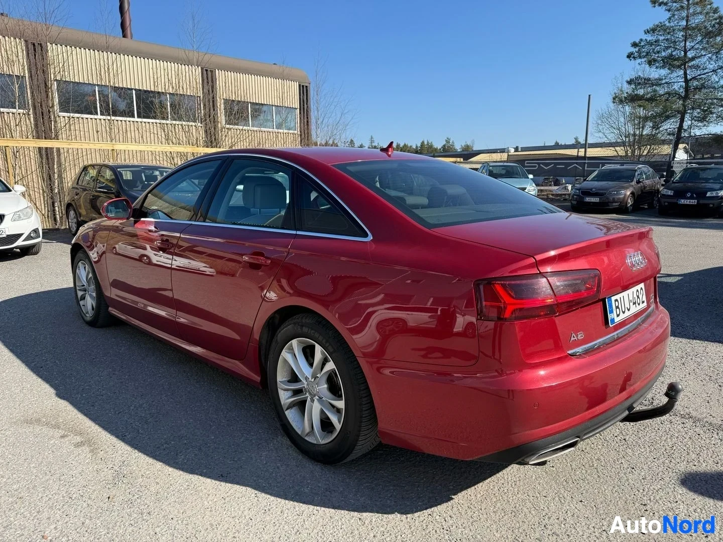 Sivulta: Punainen Audi A6 sedan näkyy sivusta oikealta puolelta, alloy wheels näkyvissä, rekisterilevy
