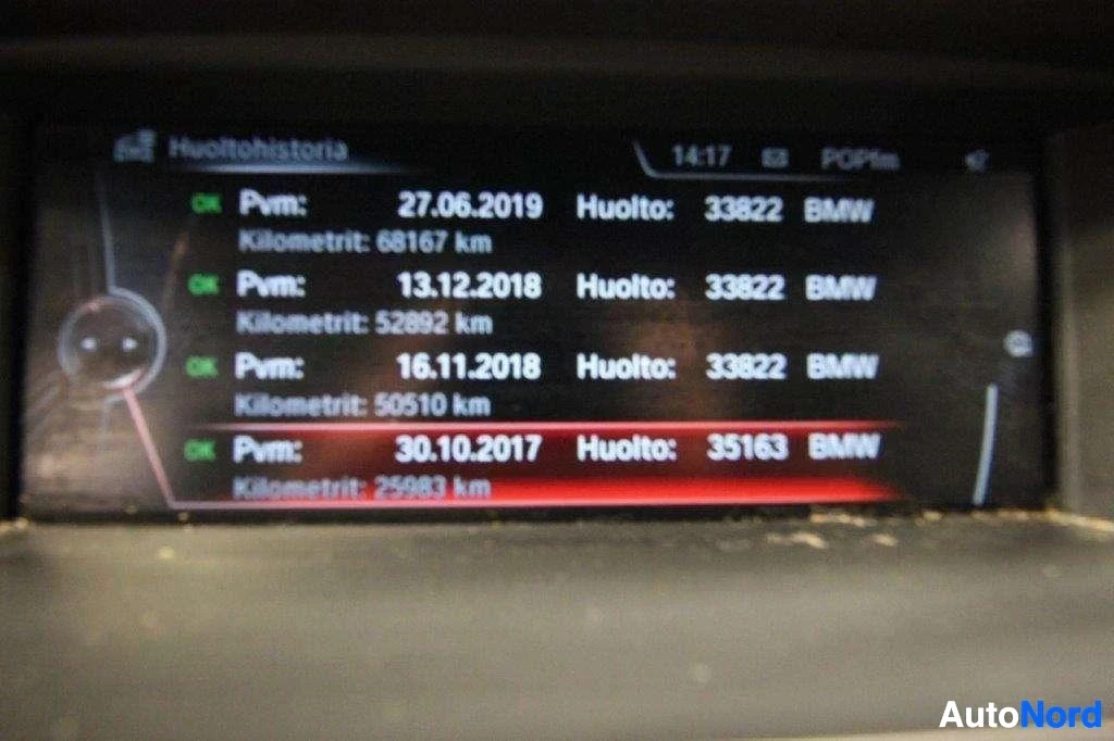 Yksityiskohta: Ajoneuvon infotainment-näytön huoltohistoria-näyttö, jossa näkyy useita huoltokirjauksia päivämäärillä, ajokilometreillä ja BMW-merkinnällä
