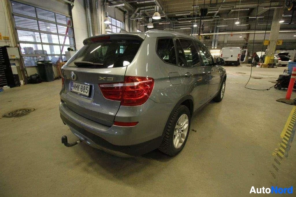 Takaviisto: Harmaa BMW X3 -maastoauto varastohallissa, takaosa ja oikea sivu näkyvissä, rekisterikilvessä NMK993