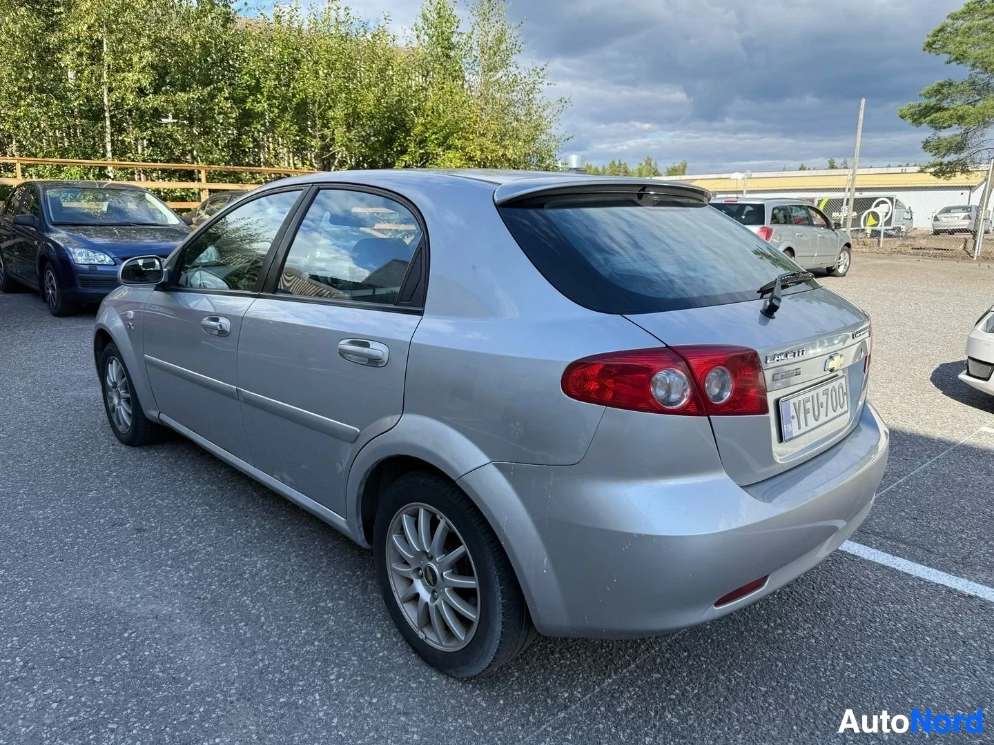 Sivulta: Hopea Chevrolet Lacetti sedan sivulta, ovi auki, rekisterikilpi, pysäköintialueella