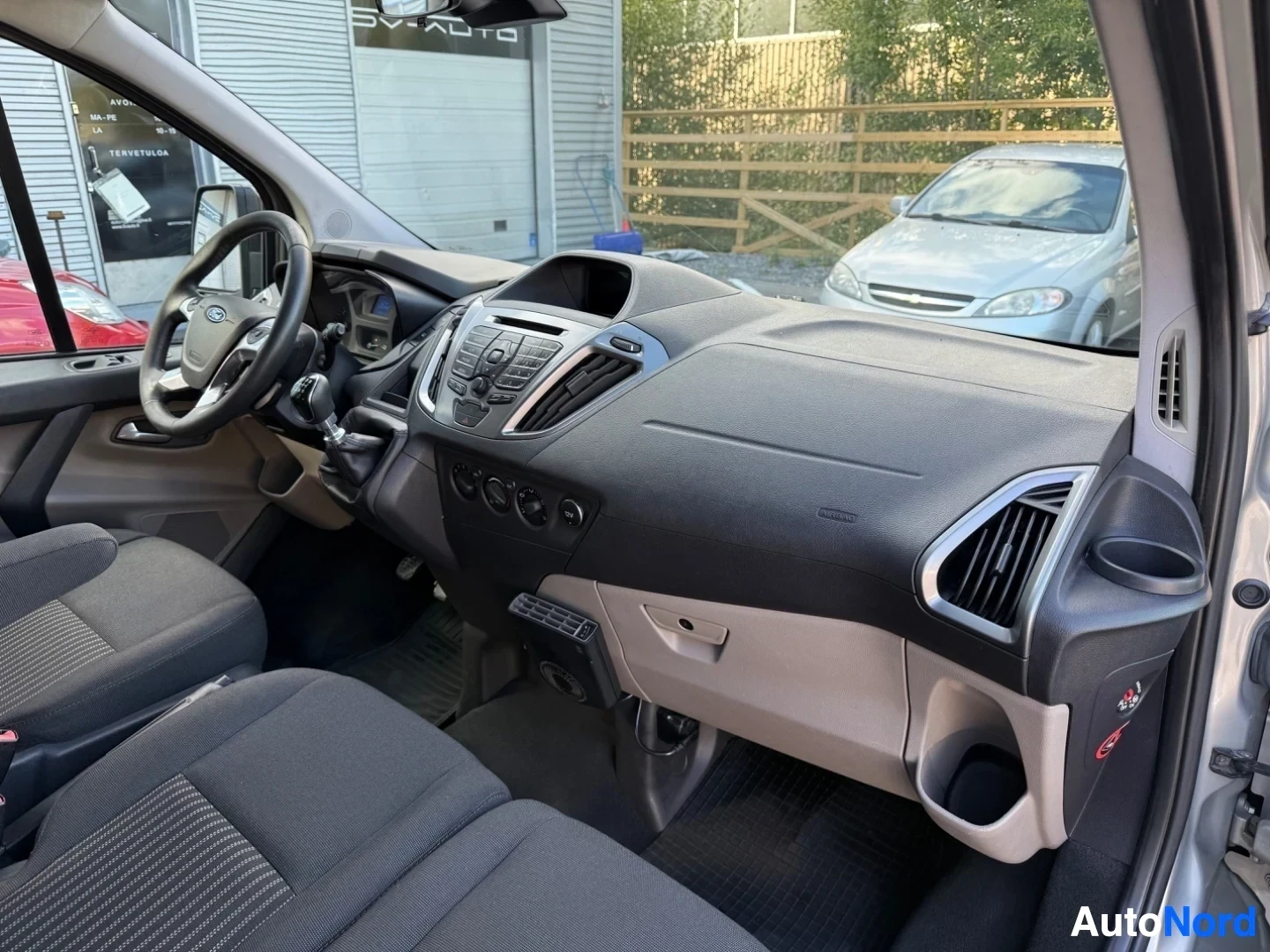 Ohjaamo: Ford Tourneo Custom sisätila oikealta puolelta, kuljettajan ratti monikäyttöpainikkeilla, siniset mittarit, keskikonsoli äänijärjestelmällä ja ilmastoinnilla, v