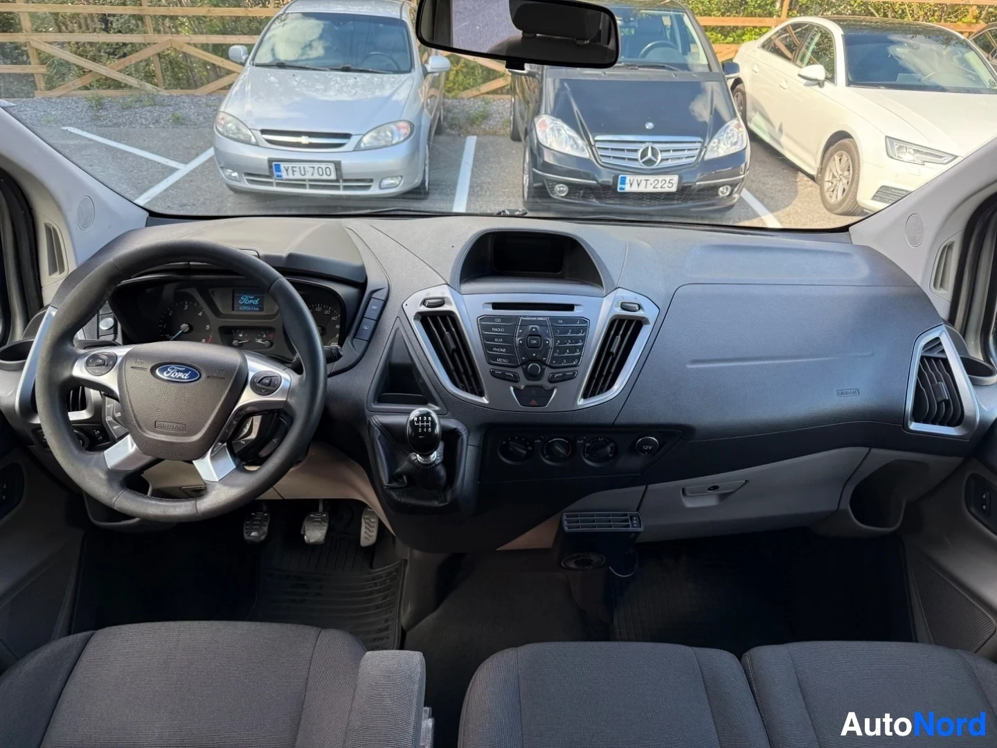 Etuistuimet: Ford Tourneo Custom sisätila, kuljettajapaikka ja ratti Ford-logolla, mustavalkoisella kahvalla varustettu monikäyttöratti, siniset värimittarit, keskikonsoli i