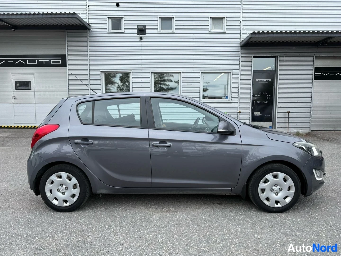 Sivulta: Harmaa Hyundai i20 sivusta oikealla puolella, punainen takalämpö näkyy vasemmalla puolella