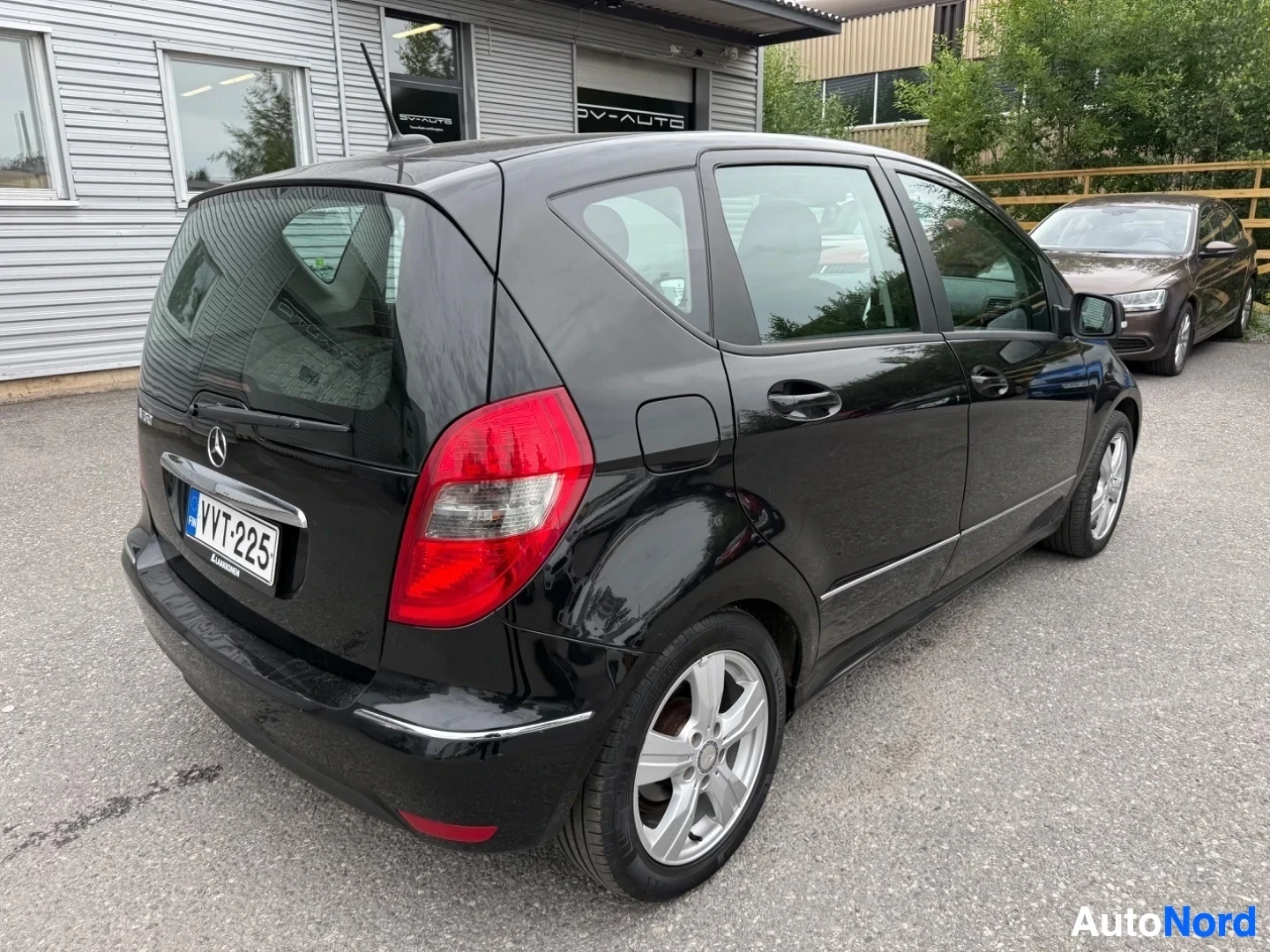 Takaviisto: Musta Mercedes-Benz A-sarja takaosa ja sivu oikealta nähtynä, punaiset takavalaisimet näkyvät, rekisterikilpi näkyvissä