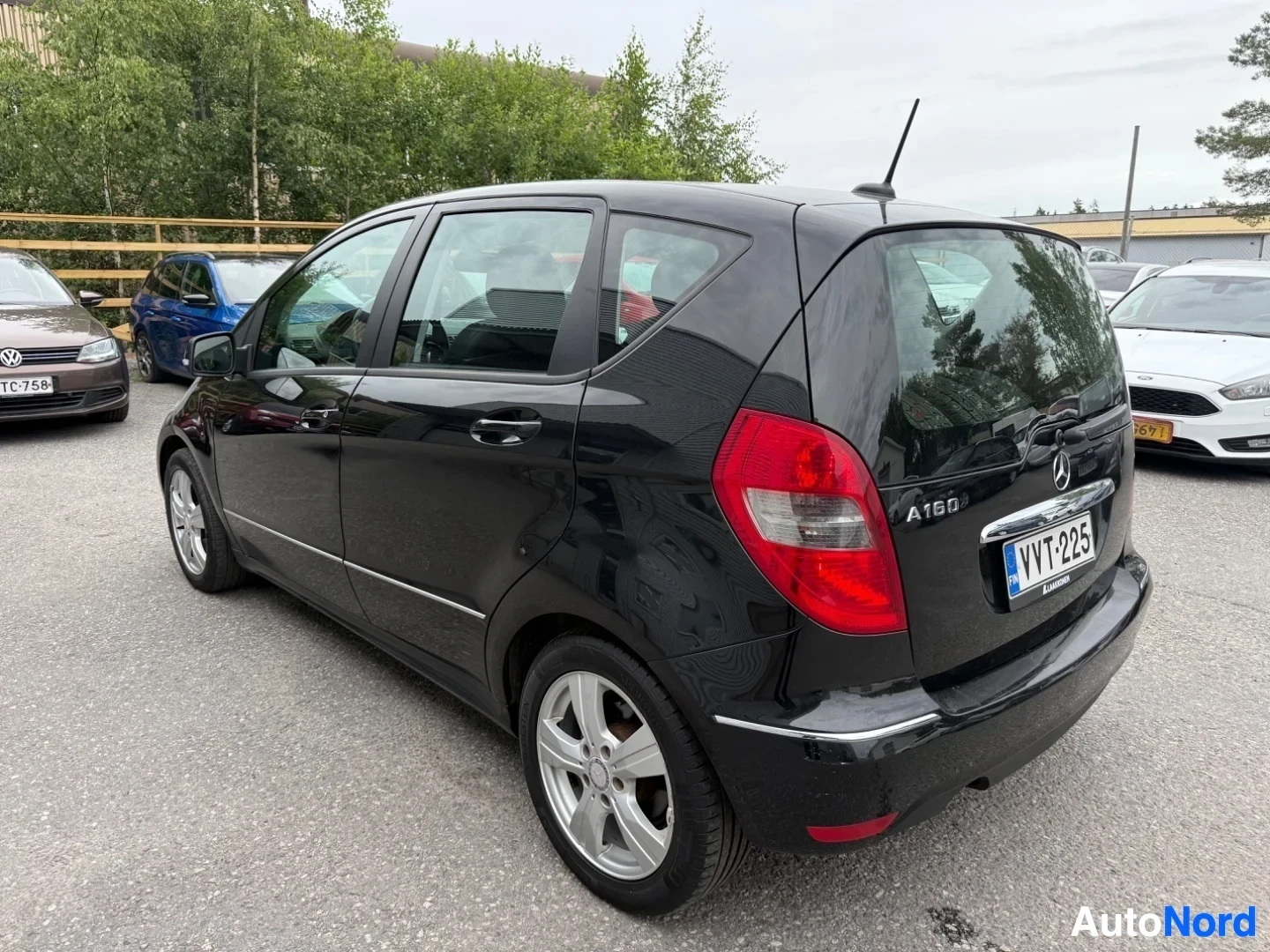 Takaviisto: Musta Mercedes-Benz A160 sivusta kuvattuna, ovi on auki, näkyvät valkokalliset vanteet