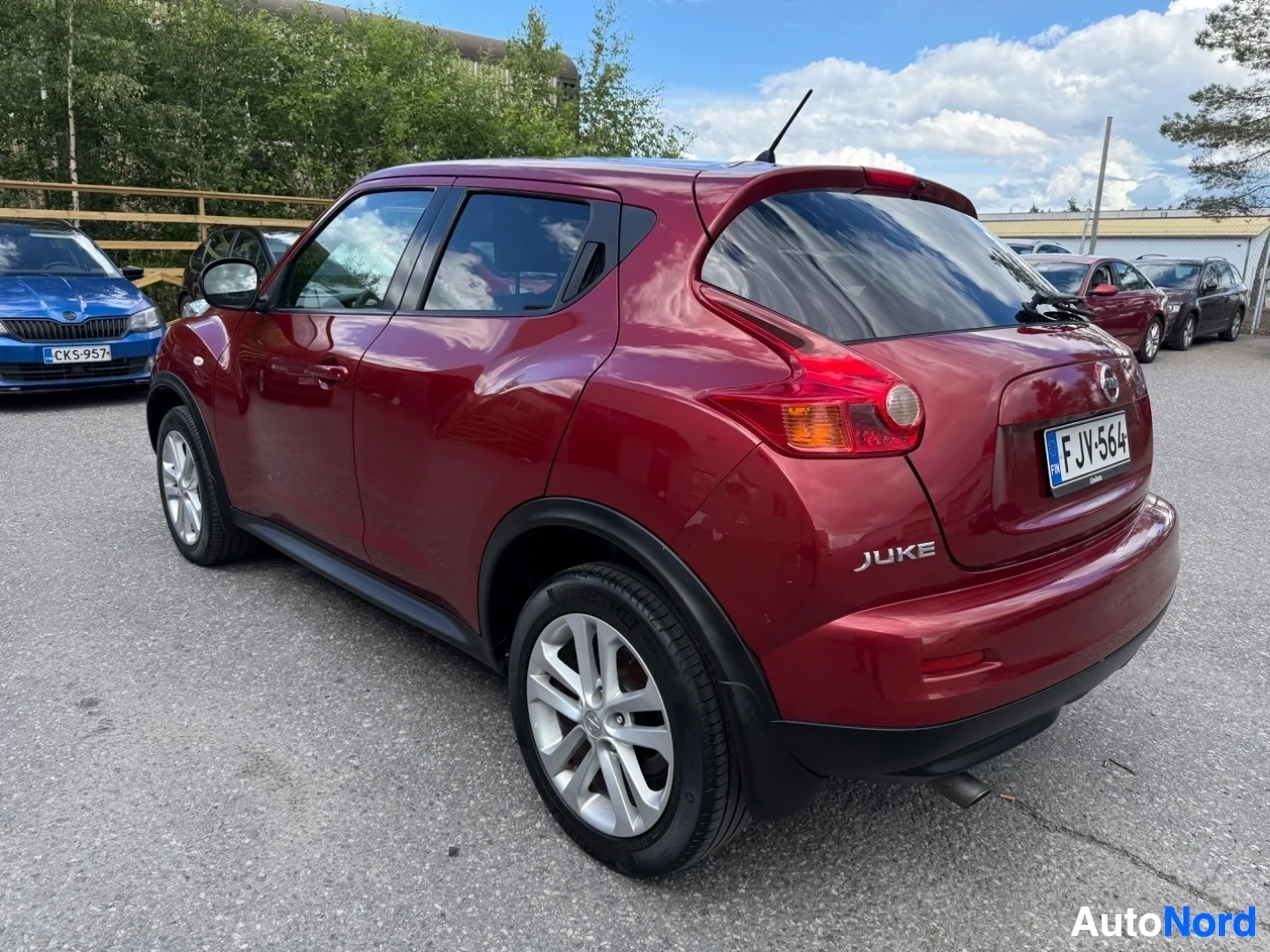 Sivulta: Punainen Nissan Juke oikealta sivulta kuvattuna. Näkyy valkoisen väriset vanteet, rekisterikilpi FJV564 ja merkinnät "JUKE" sivulla.