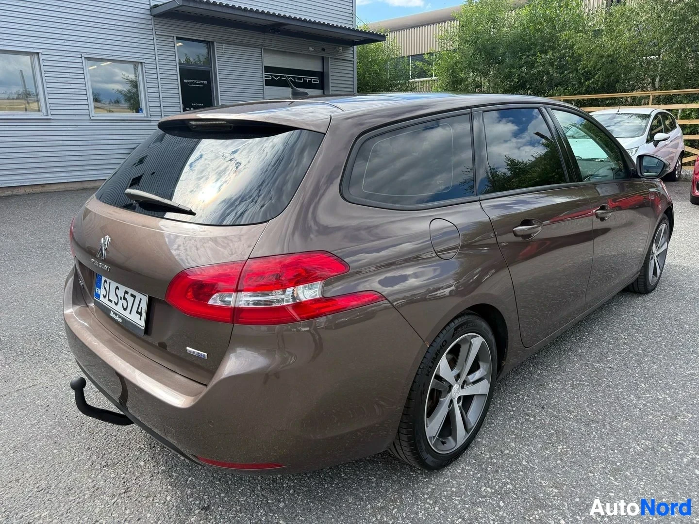Takaviisto: Ruskea Peugeot 308 SW farmari, kuvattu oikealta sivulta taakse päin. Rekisterikilpi SLS574 näkyvissä. Auton takana näkyy kytkentäpallo.