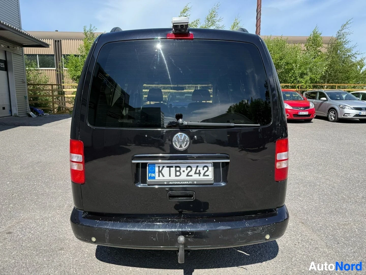 Takaa: Musta Volkswagen-pakettiauton takaosa, jossa on rekisterikilvellä ja punainen kattomoduuli