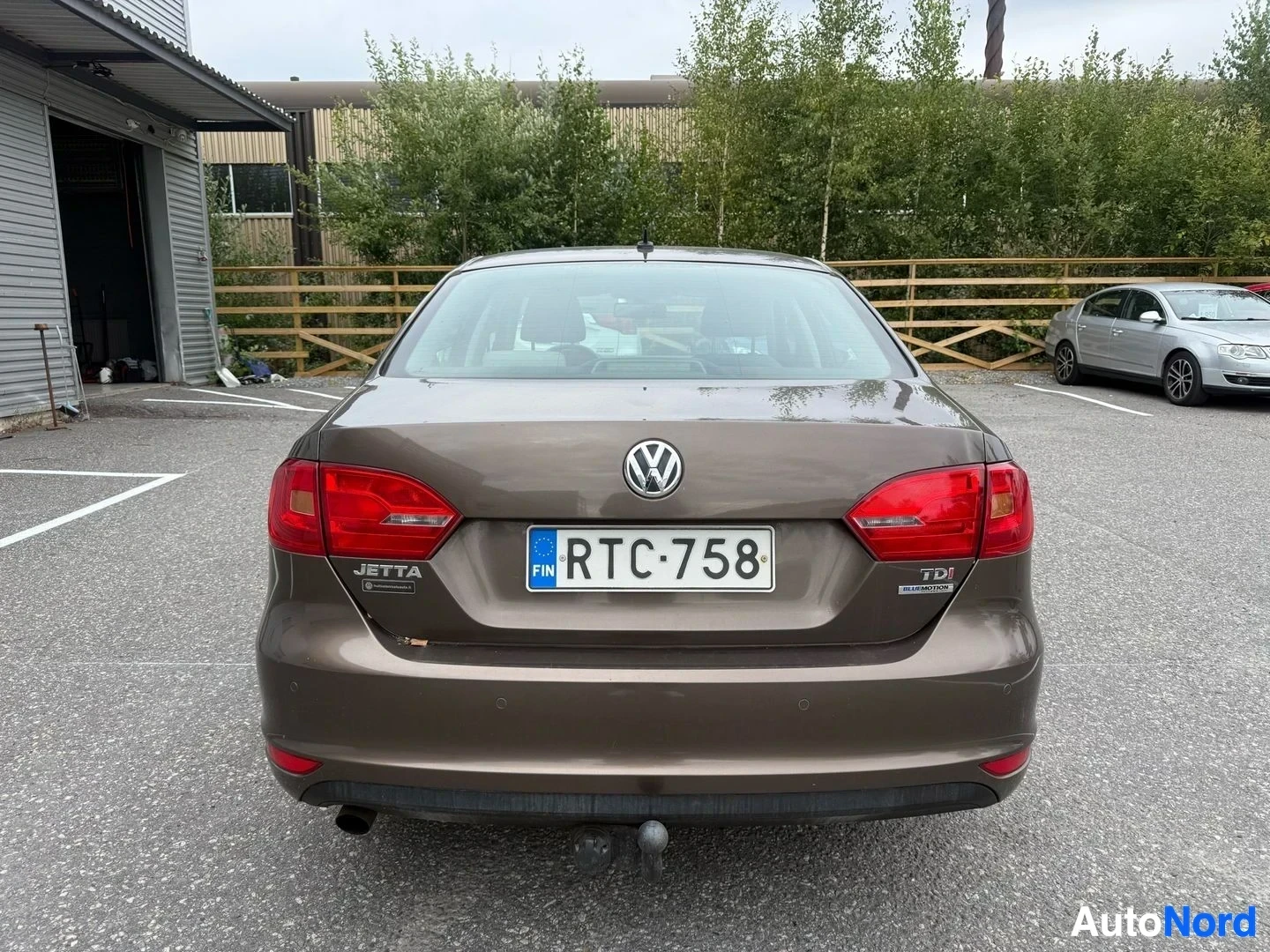 Takaa: Volkswagen Jetta taakse katsottu, ruskea sedan pysäköitynä parkkipaikalle, rekisterikilvessä, näkyy TDI-merkintä takalisässä