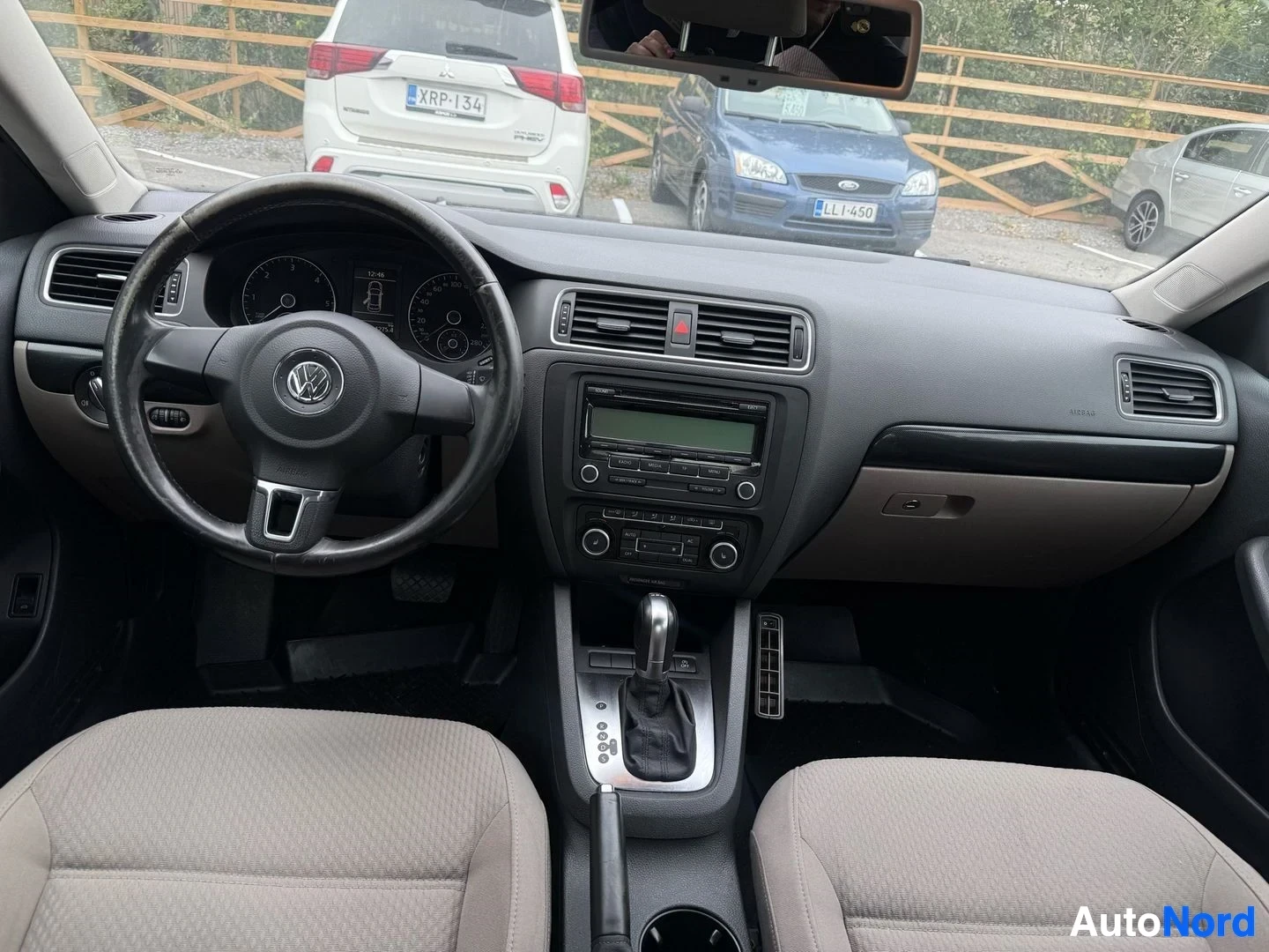 Ohjaamo: Volkswagen-ohjaamon sisänäkymä: VW-logoilla varustettu ohjauspyörä, LCD-näytöllinen instrumenttipaneeli, ilmastointi-säädöt, CD-radioyksikkö ja beige verhoillut