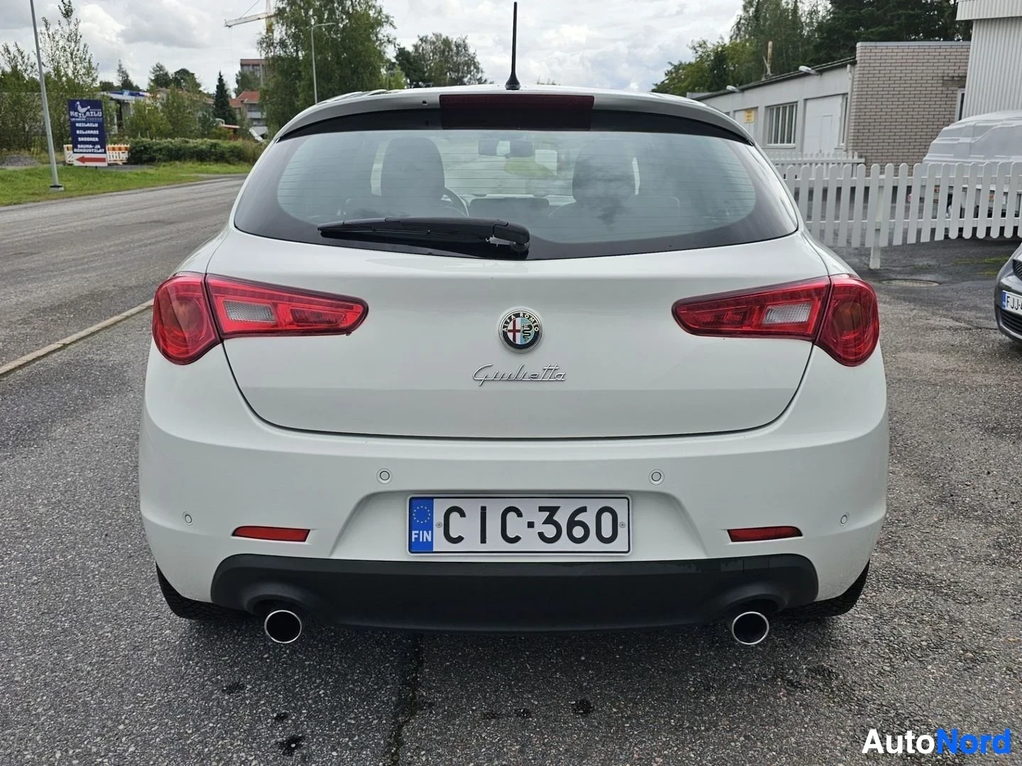 Takaa: Valkoinen Alfa Romeo Giulietta, takanäkymä suoraan, kaksi punaista takavalaistinta, dual exhaust