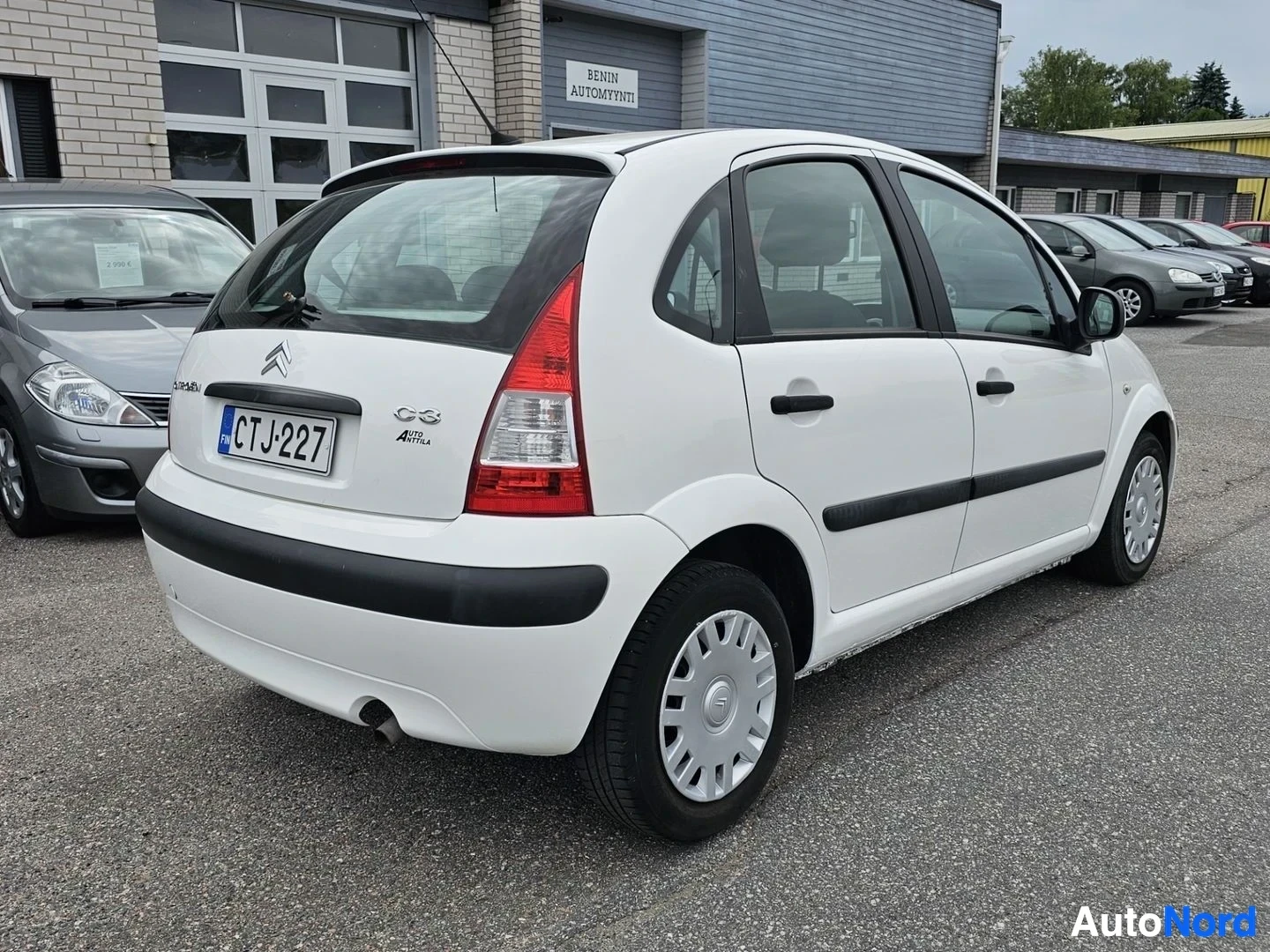 Takaviisto: Valkoinen Citroën C3, takaoikeasta näkymä, pysäköitynä autoliikkeen pihalla