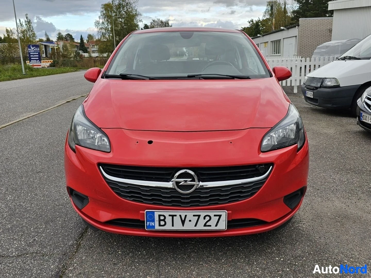 Edestä: Punainen Opel Corsa kolmen hengen pakettiauto suoraan edestä päin kuvattuna, mustalla etugrillillä ja Opel-logolla.