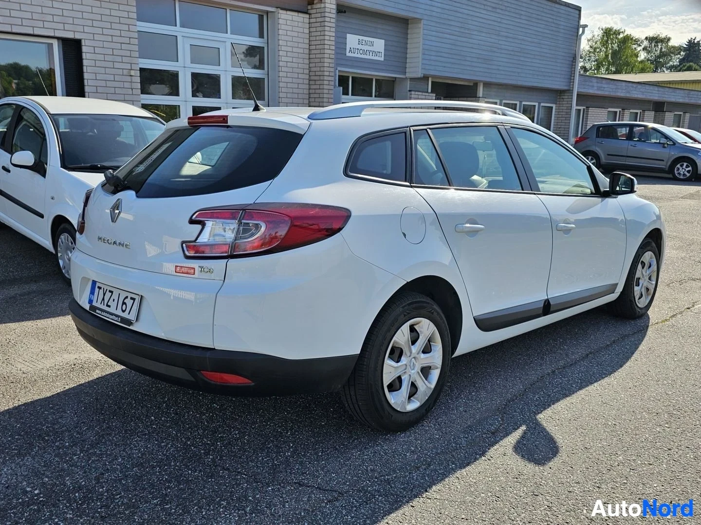 Takaviisto: Valkoinen Renault Megane farmari, takaa oikealta, parkkipaikalla hallinnon rakennuksen vieressä